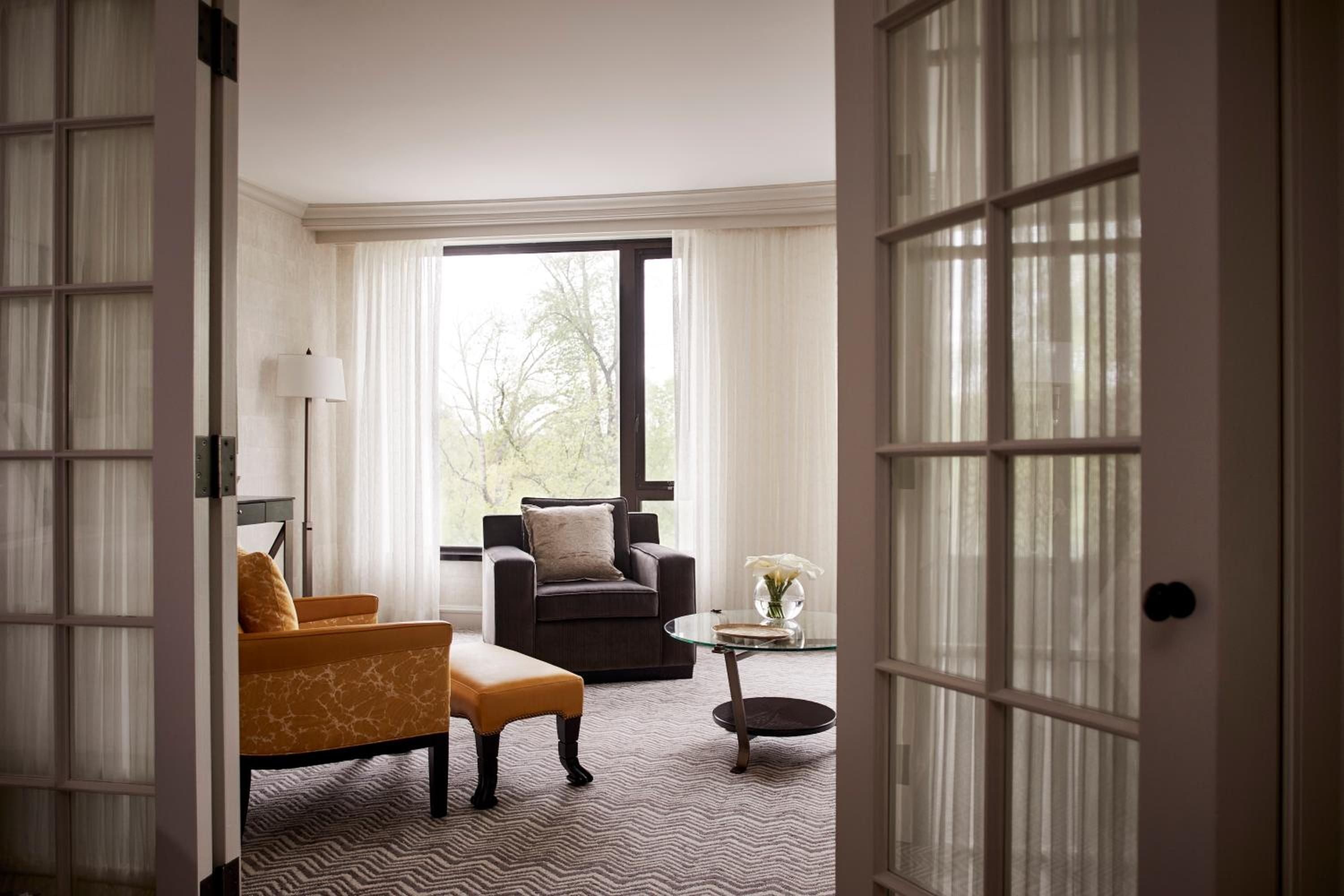 French doors frame an elegant sitting area where burnished leather meets charcoal velvet, while afternoon light filters through sheer curtains overlooking Boston's tree-lined streets.