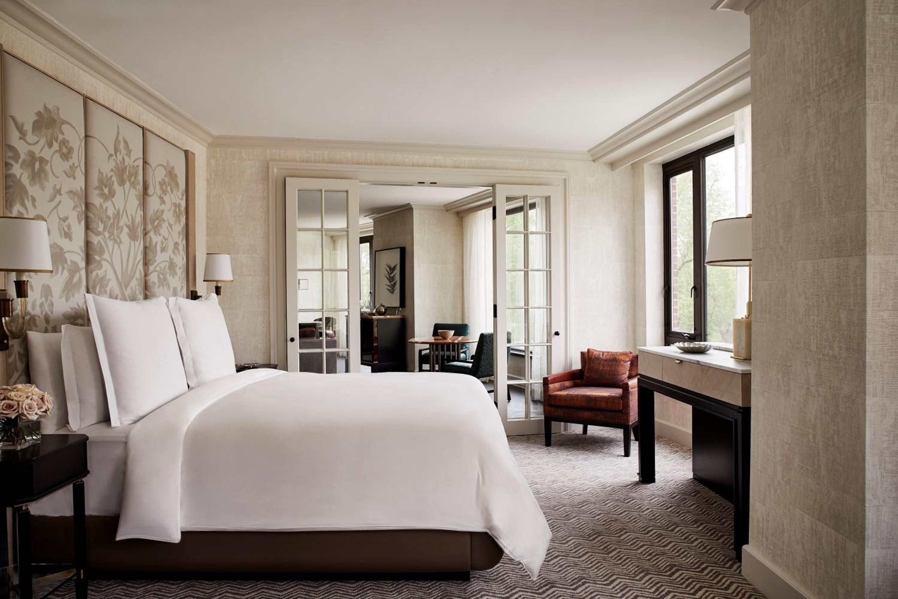 Neutral botanicals frame the plush king bed while French doors reveal glimpses of an elegant sitting area, creating an intimate residential sanctuary above Boston's bustling streets.