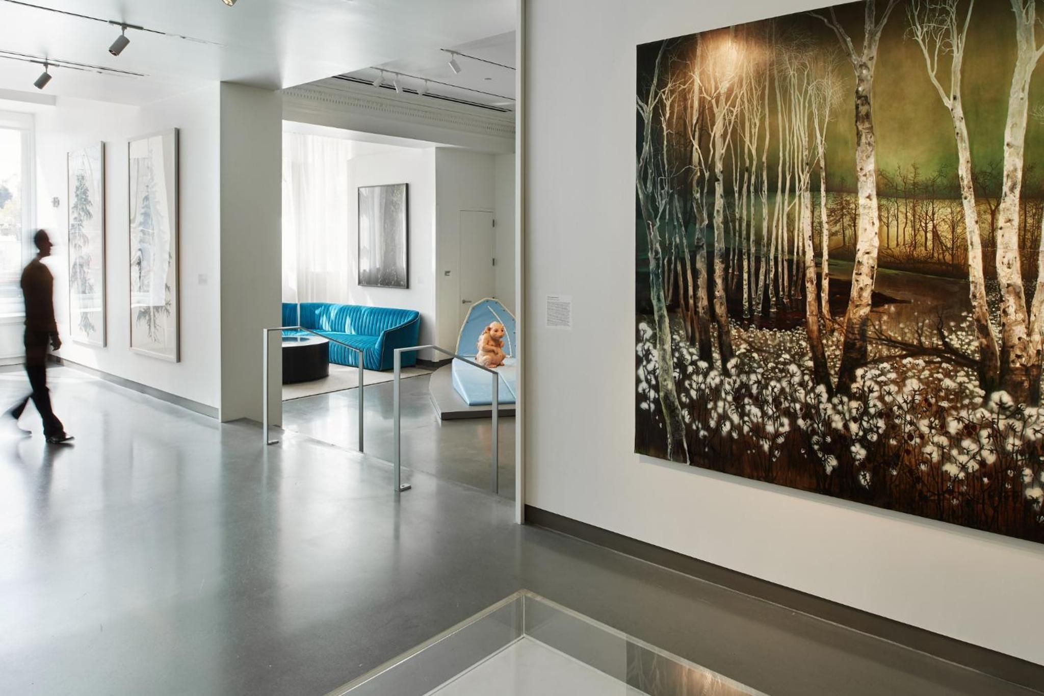 Contemporary art transforms sleek corridors into gallery spaces, where birch forest murals and modern seating create an unexpectedly intimate moment within the museum hotel's pristine white halls.
