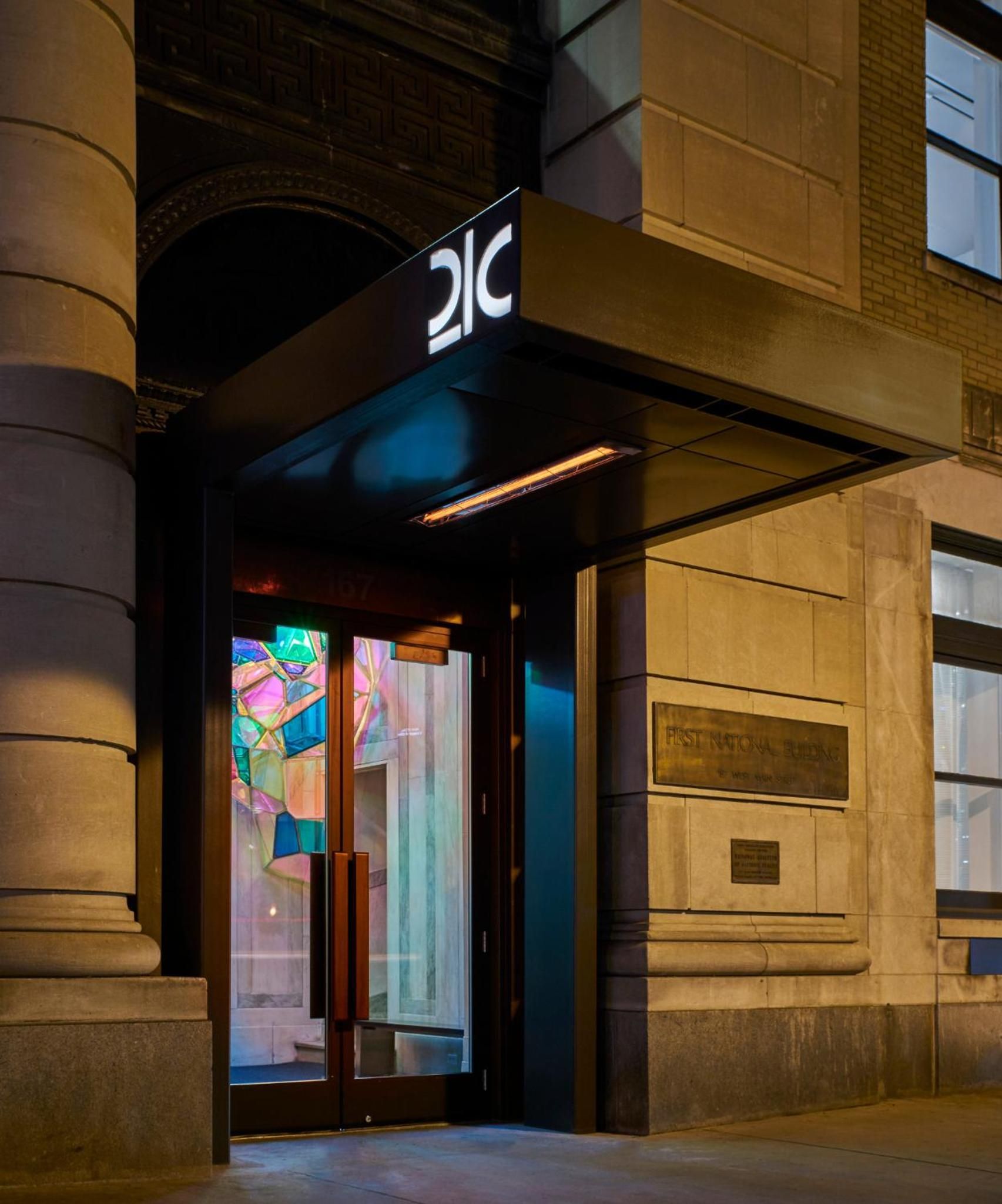 Colorful dichroic glass panels catch evening light at the hotel's street-level entrance, where contemporary art meets historic limestone architecture in downtown Lexington.