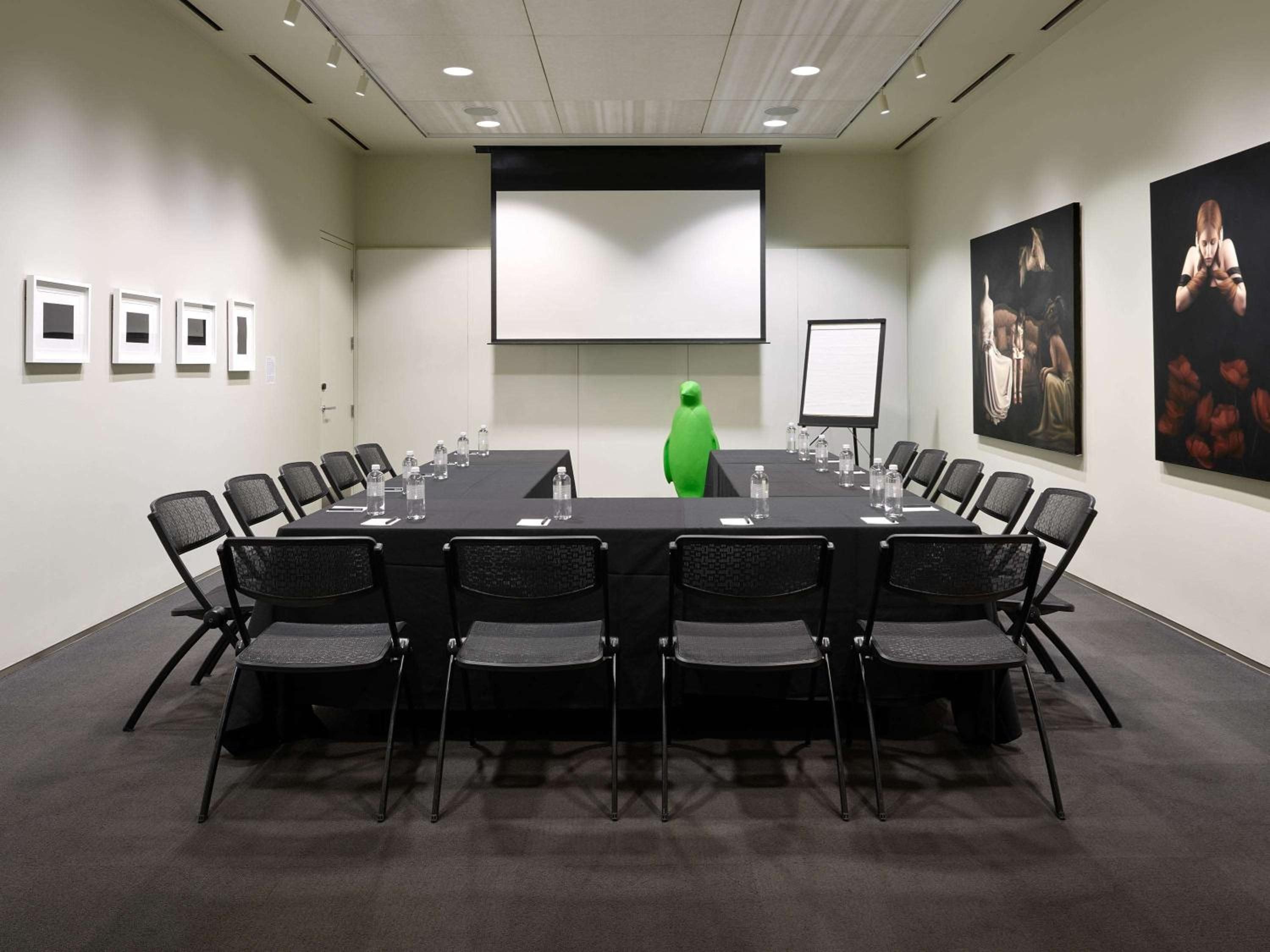 Contemporary boardroom blends business with art, where vibrant paintings and a whimsical green penguin sculpture transform corporate meetings into creative encounters.