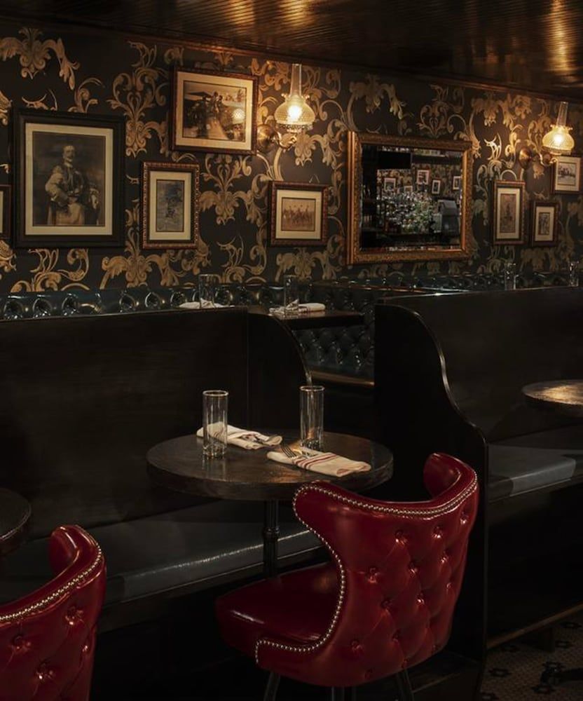 Gilded wallpaper and crimson leather create an intimate speakeasy atmosphere where vintage portraits watch over candlelit conversations and perfectly poured spirits.