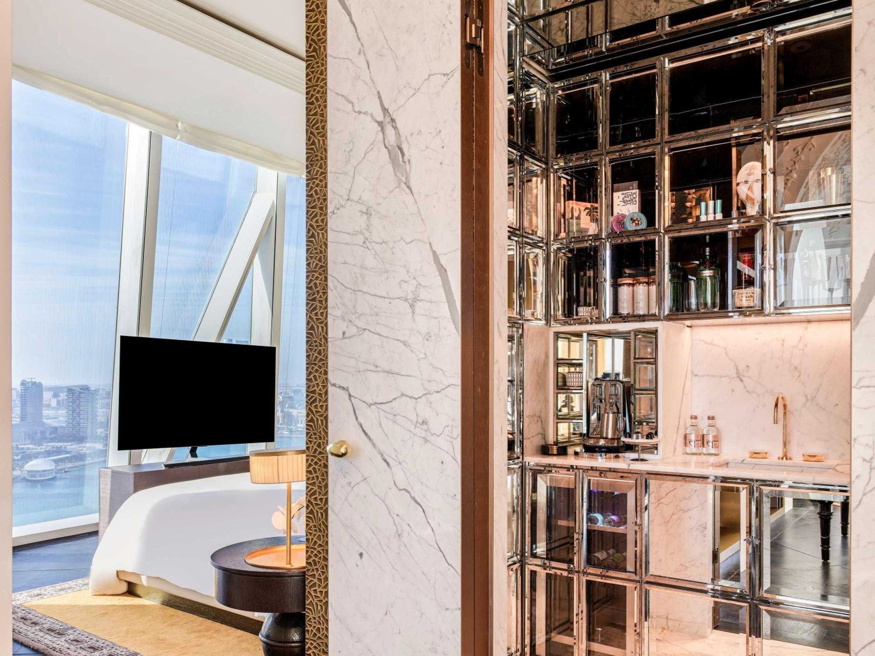 Mirrored cabinetry and Calacatta marble create a jewel-box bar within the suite, where crystal decanters catch afternoon light streaming through floor-to-ceiling windows overlooking Doha's skyline.