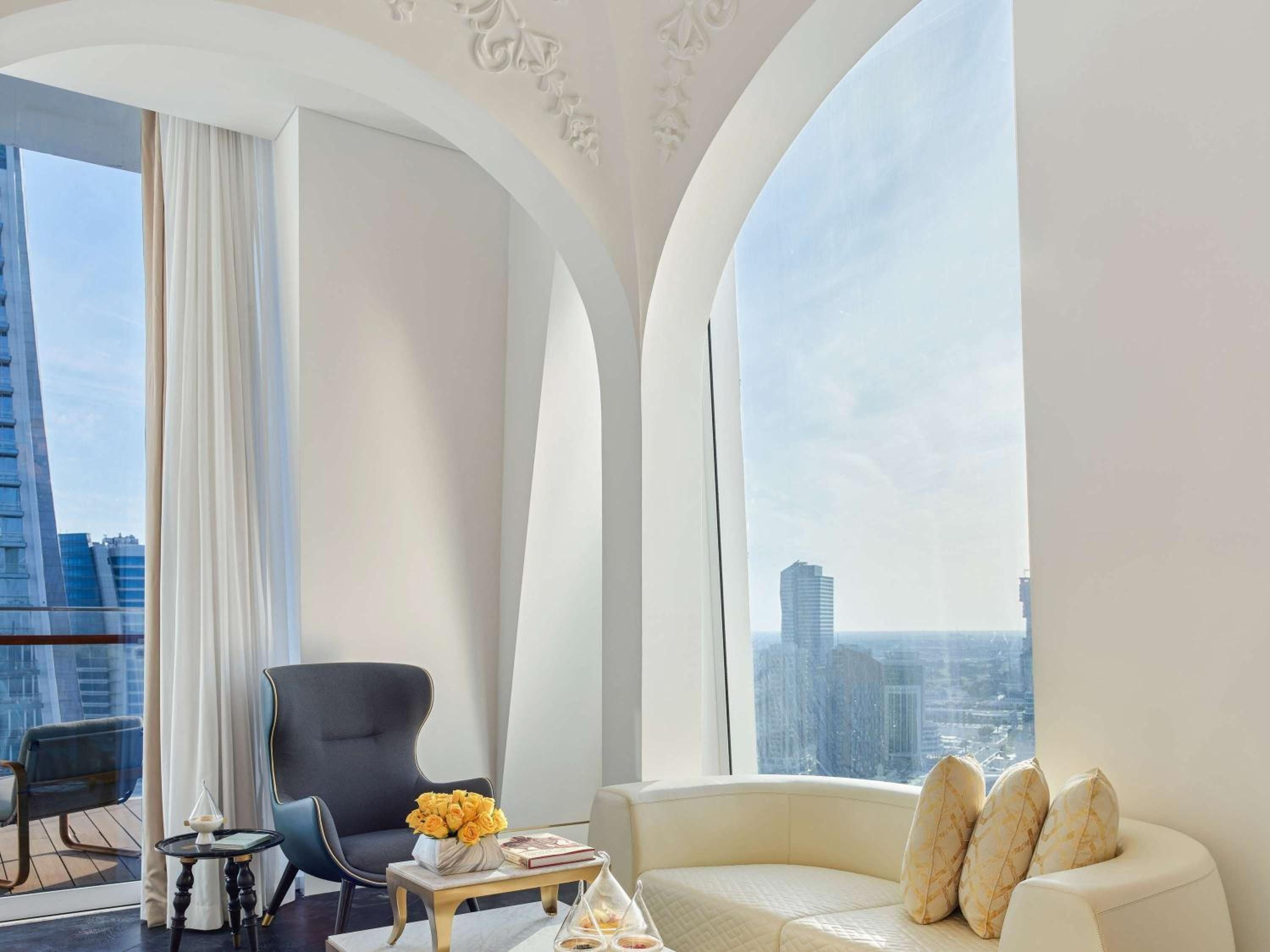 Graceful arches frame Dubai's skyline from this corner suite, where creamy furnishings and decorative ceiling details create an oasis of refined elegance high above the city.