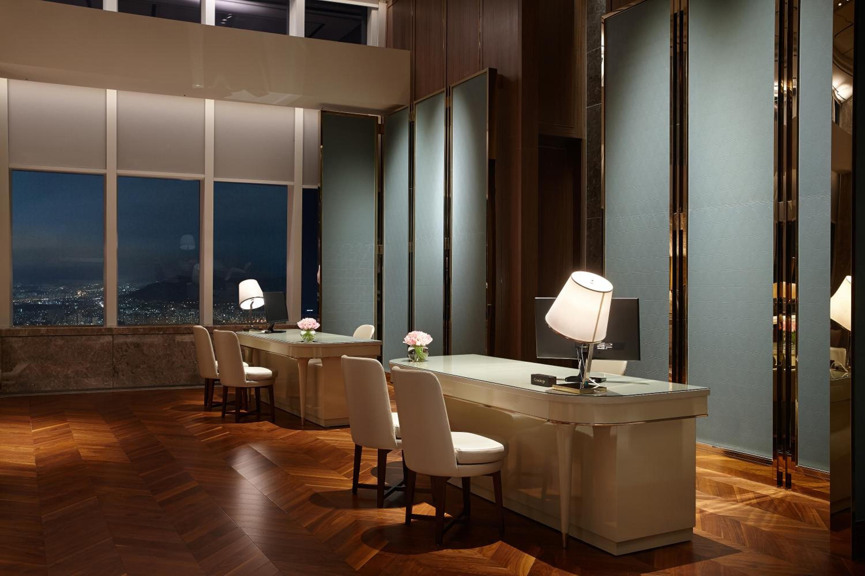 Floor-to-ceiling windows frame Seoul's glittering skyline while warm parquet floors and contemporary furnishings create an intimate workspace high above the city's pulse.