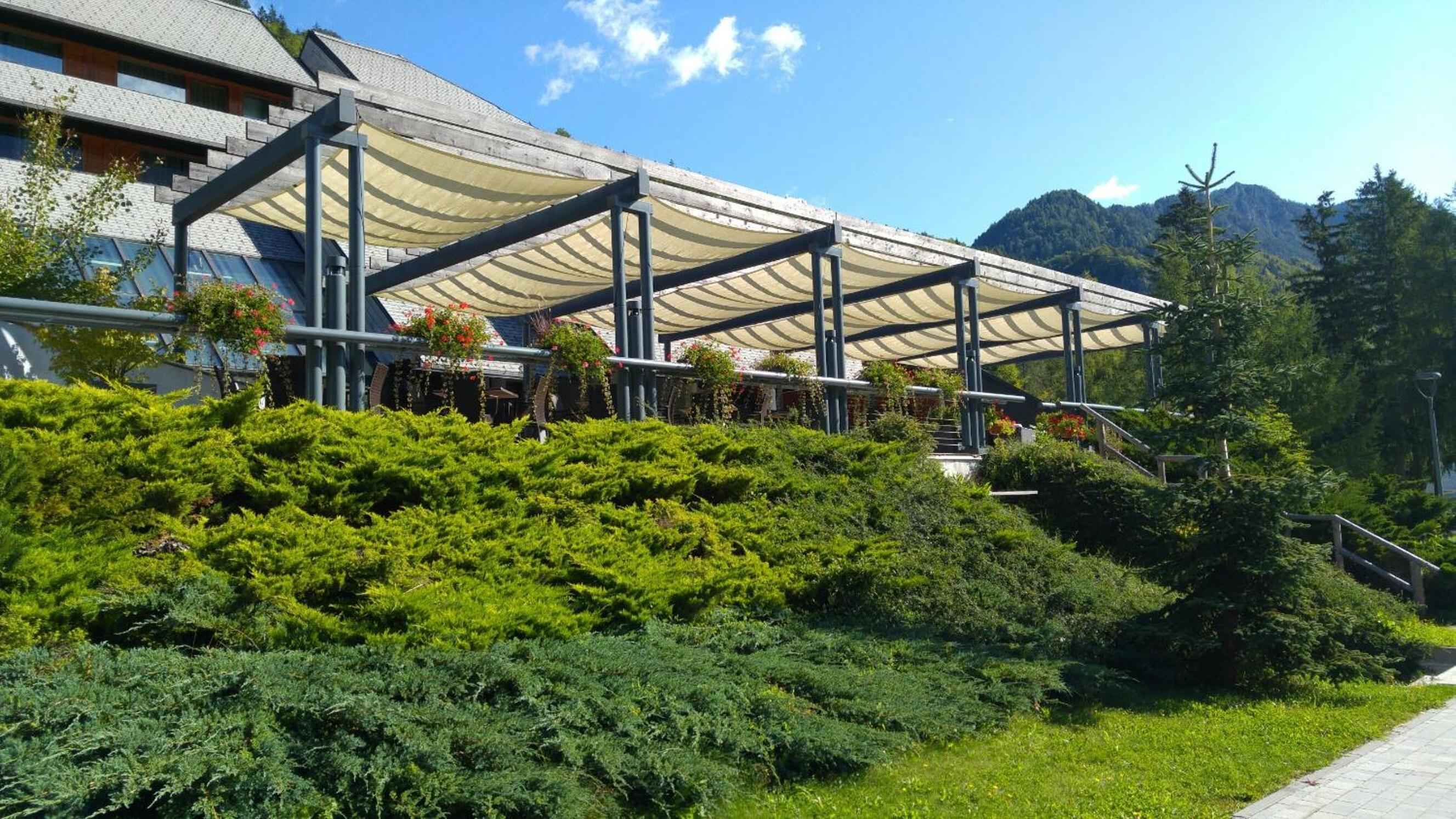 Retractable awnings shade private terraces where flowering baskets cascade toward Alpine meadows, creating intimate outdoor sanctuaries against Slovenia's dramatic mountain backdrop.
