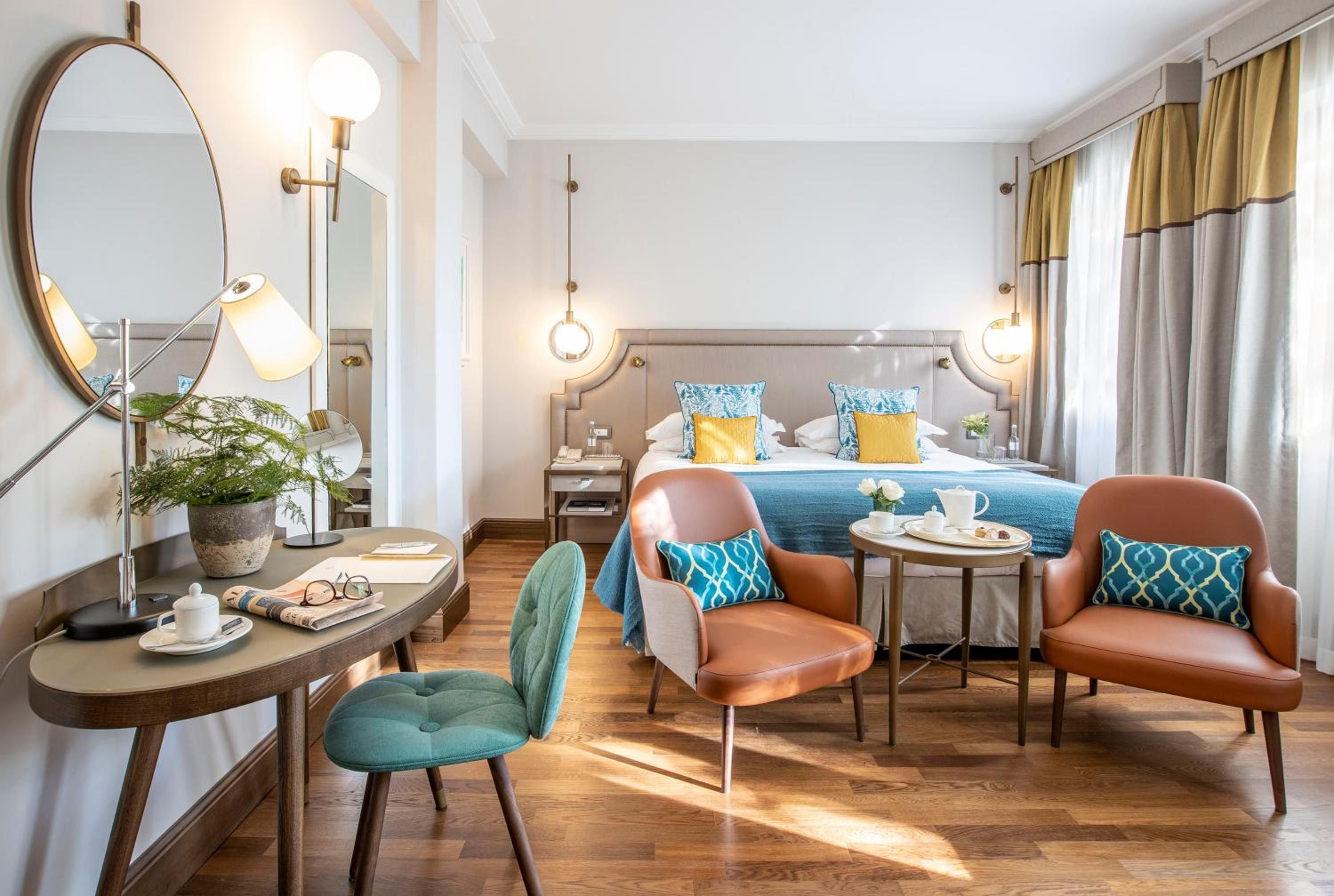 Warm leather armchairs and teal accents create an intimate seating area where morning espresso feels ceremonial, bathed in golden Tuscan light.