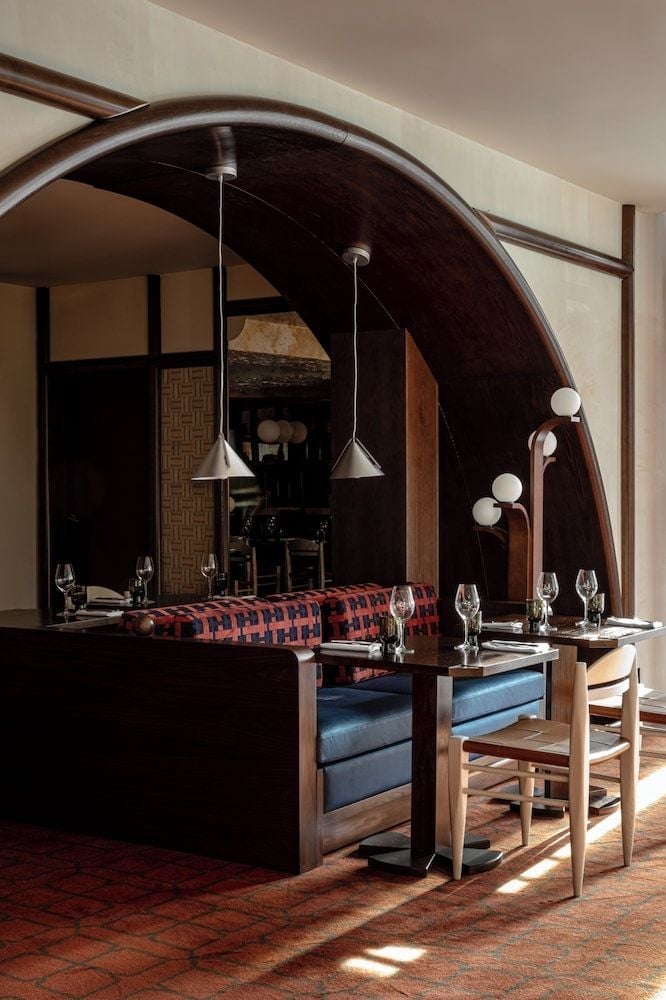 Arched dining nooks frame intimate tables where pendant lights cast warm pools over rustic wood and plaid upholstery, creating an alpine refuge for leisurely meals.