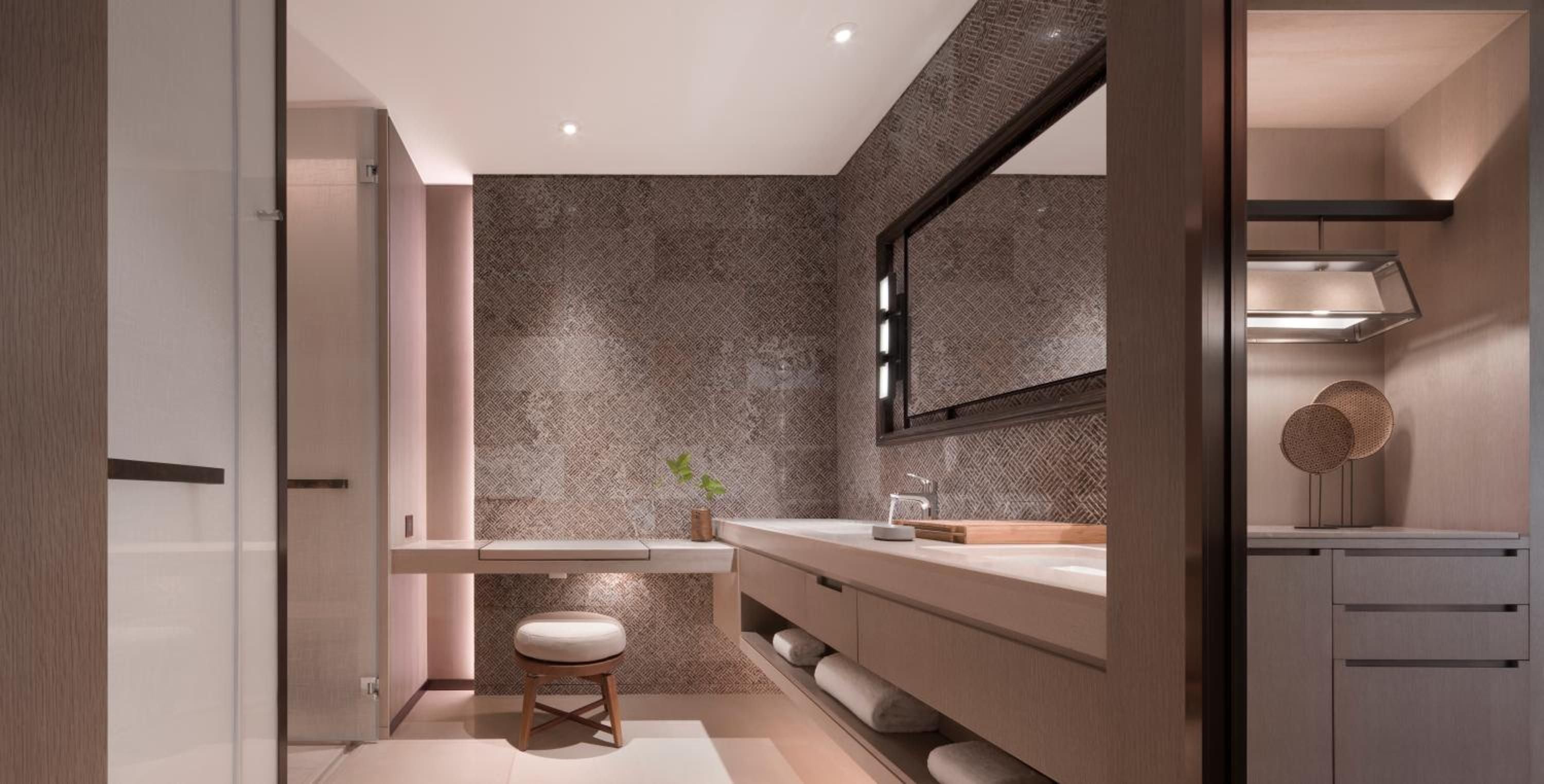Warm wood vanities and textured bronze tiles create a spa-like sanctuary where contemporary luxury meets tactile craftsmanship in this serene master bath.