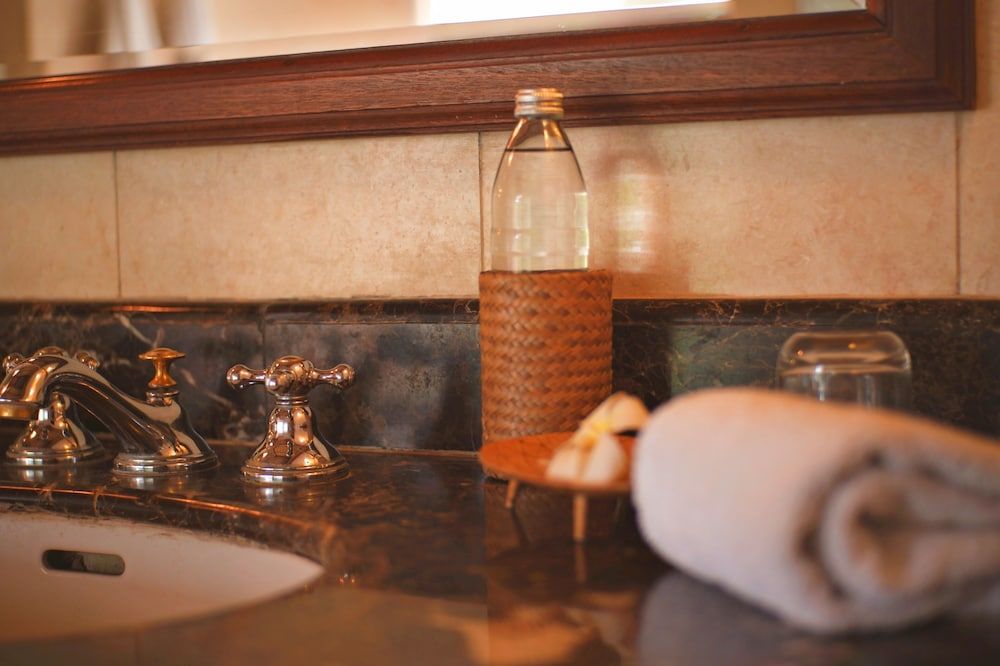 Brass fixtures gleam against dark marble while woven textures and rolled towels create an intimate spa-like sanctuary in this thoughtfully appointed guest bathroom.