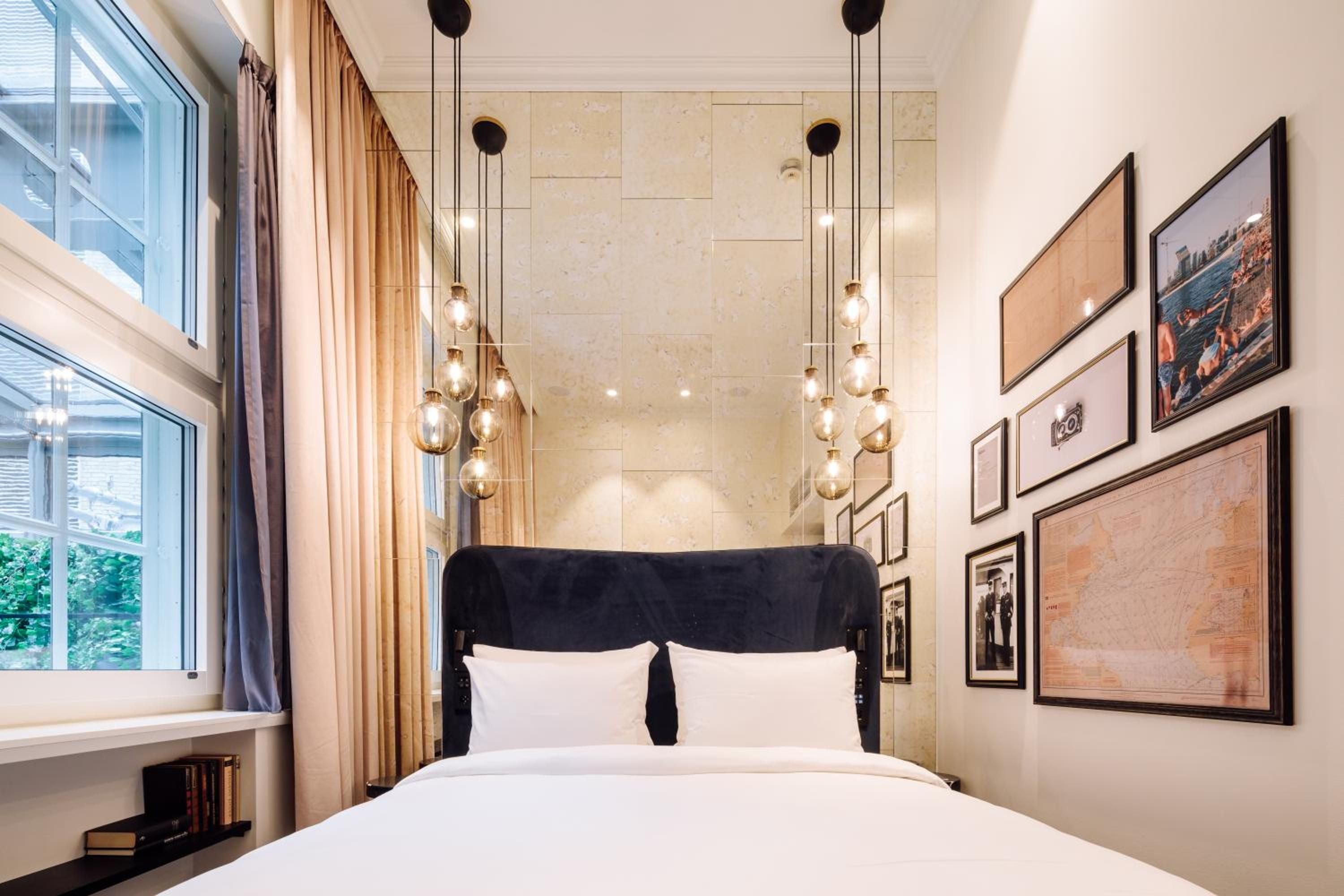 Pendant lighting clusters illuminate a sophisticated guest room where contemporary Scandinavian design meets warm textures, creating an intimate sanctuary above Oslo's bustling streets.
