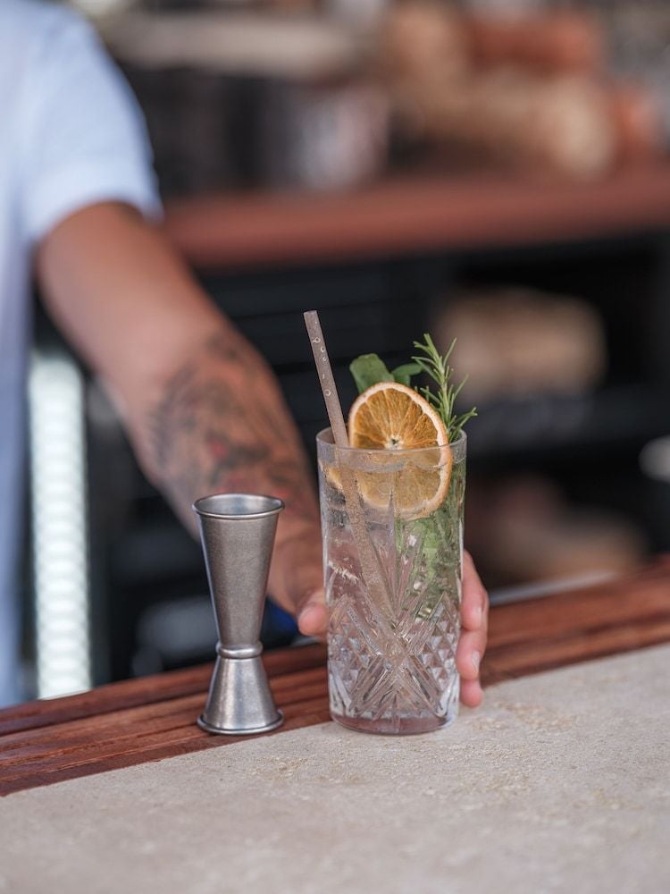 Crystal-cut glassware catches afternoon light as skilled bartenders craft herb-infused cocktails, their tattooed hands a testament to modern mixology artistry at this sophisticated poolside bar.