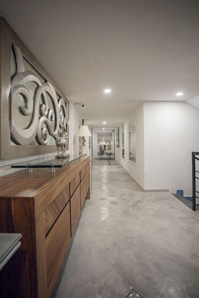 Polished concrete floors and warm walnut cabinetry create sophisticated contrast in this gallery-like corridor, where contemporary art commands attention beneath recessed lighting.