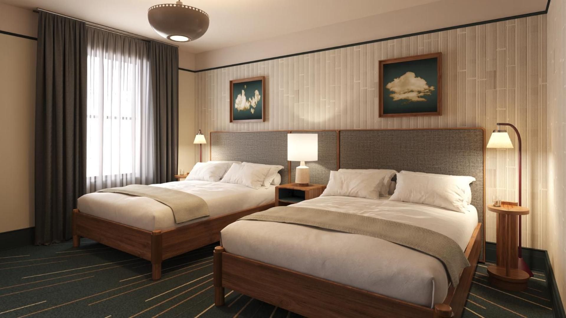 Twin beds with charcoal upholstered headboards anchor this sophisticated guest room, where vintage cloud paintings and warm wood tones create an unexpectedly cozy urban retreat.