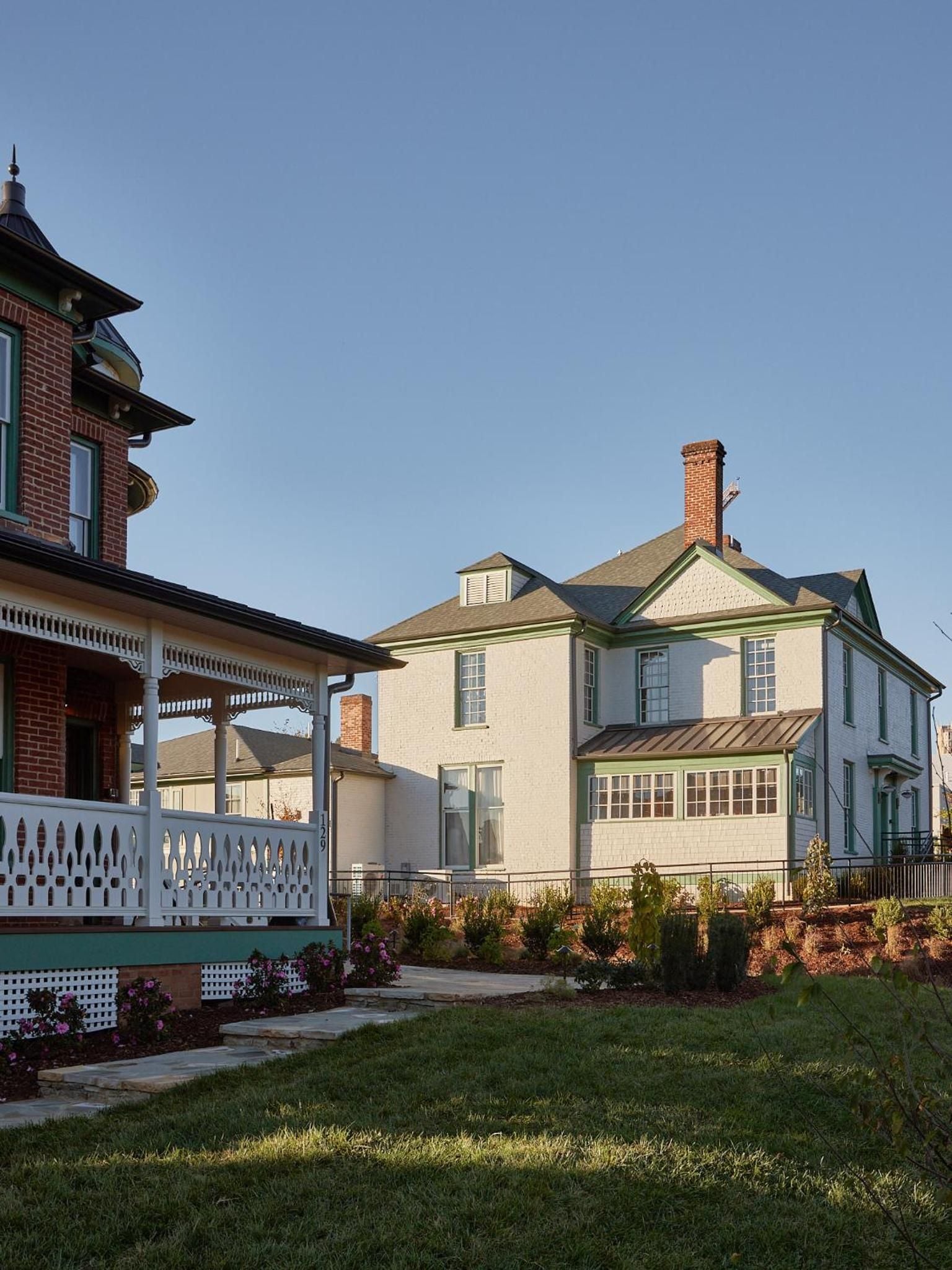 Victorian gingerbread trim and wraparound porches create an enchanting streetscape where manicured gardens frame historic architecture beneath golden hour light.