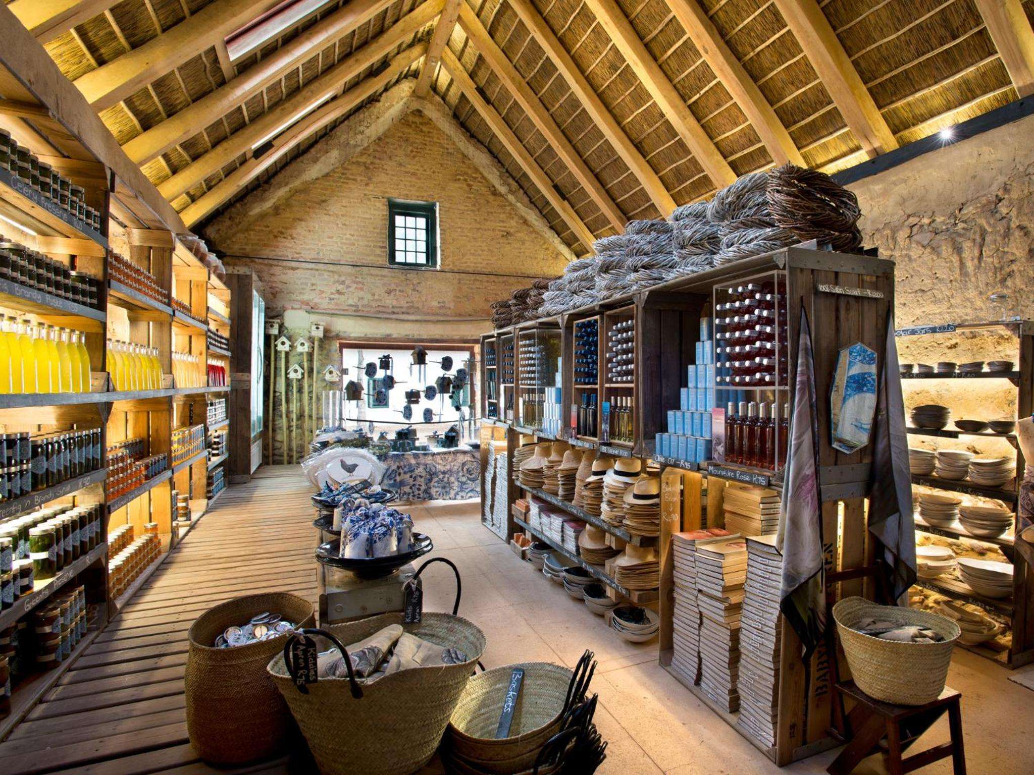 Rustic wooden shelves showcase handcrafted ceramics and traditional tools beneath exposed timber beams, transforming this heritage workshop into a captivating artisanal display space.