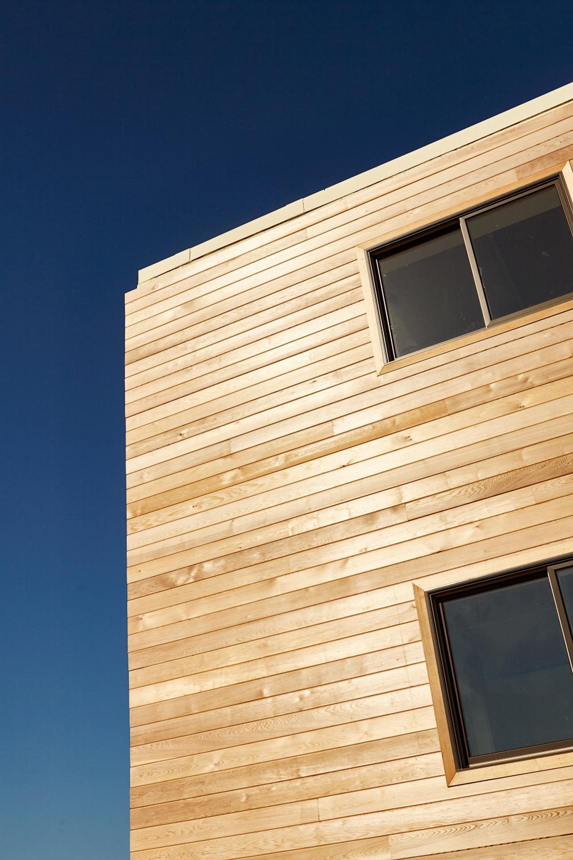 Cedar shingles catch golden hour light on Marram's modernist facade, where clean-lined windows frame ocean views beyond the minimalist geometry.
