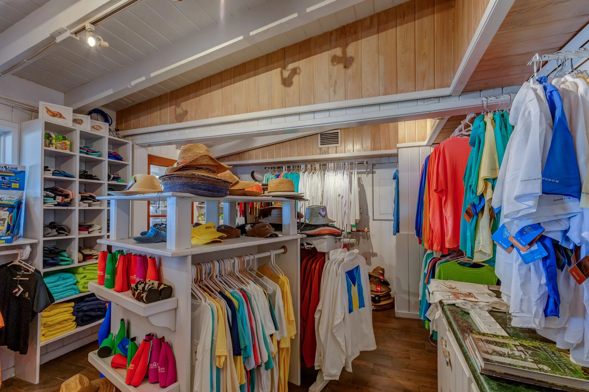 Bright tropical apparel and woven sun hats fill the resort's cheerful boutique, where wood-paneled walls and white shelving create a breezy island shopping experience.