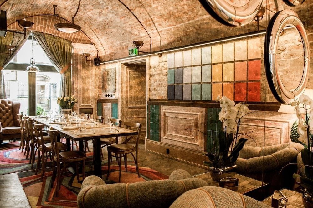 Exposed brick arches and jewel-toned tile mosaics create an intimate dining sanctuary where candlelit tables beckon beneath vaulted ceilings in this atmospheric underground space.