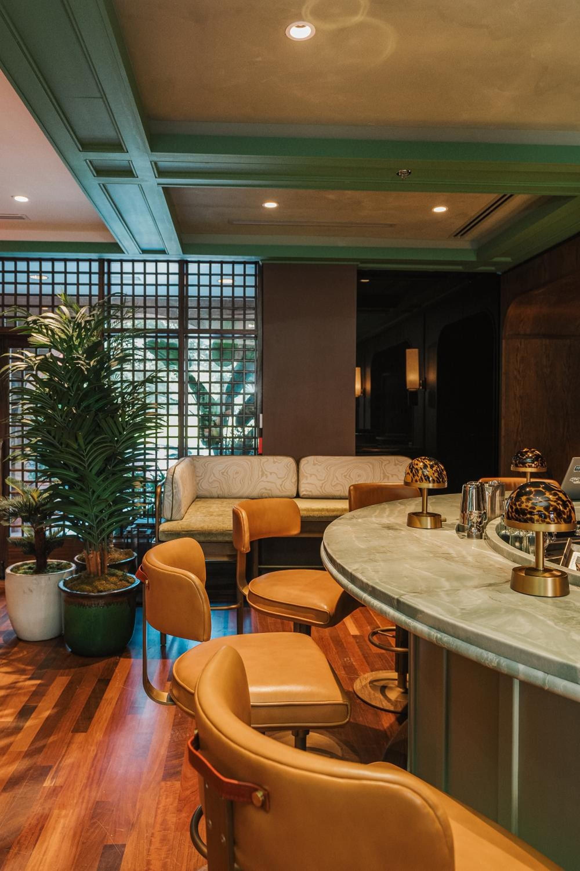 Warm leather swivel stools invite lingering at the marble-topped bar, where tortoiseshell pendant lamps cast an intimate glow over afternoon cocktails.