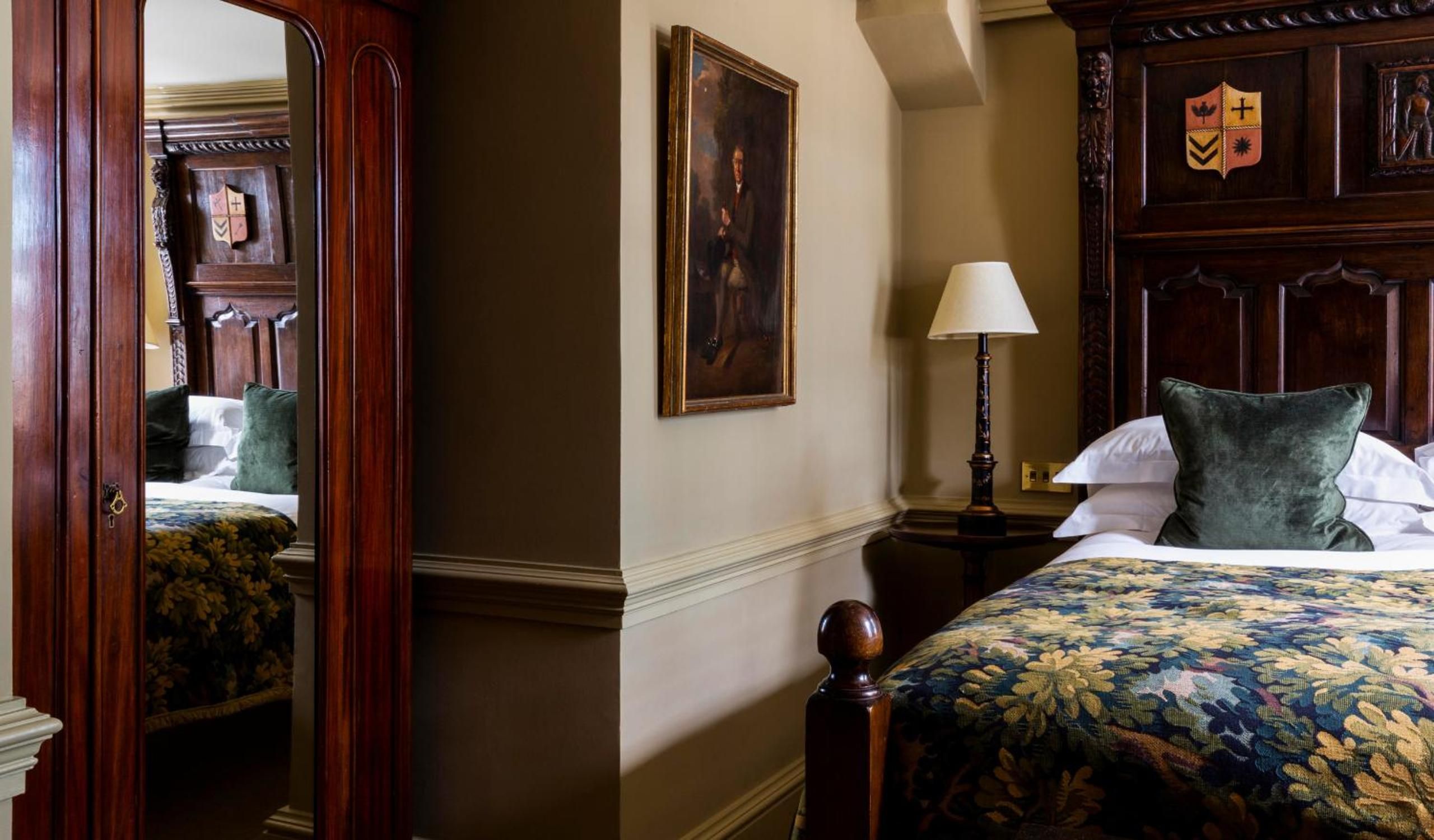 Rich mahogany paneling and velvet cushions create an intimate sanctuary where Georgian elegance meets modern comfort in this thoughtfully restored historic bedroom.
