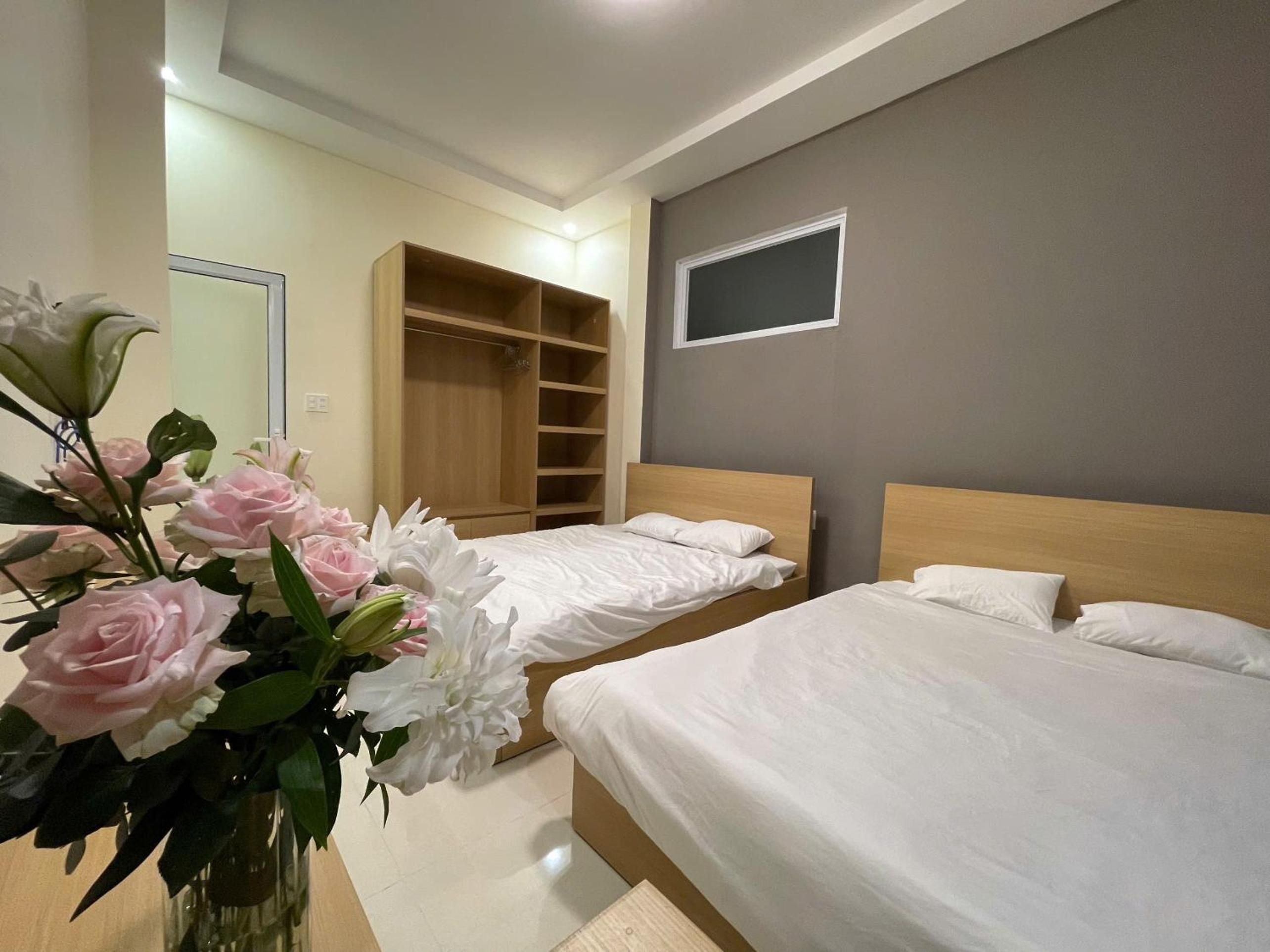 Twin beds with warm wood headboards create an intimate retreat, while fresh roses and chrysanthemums add a personal touch to this thoughtfully appointed guest room.