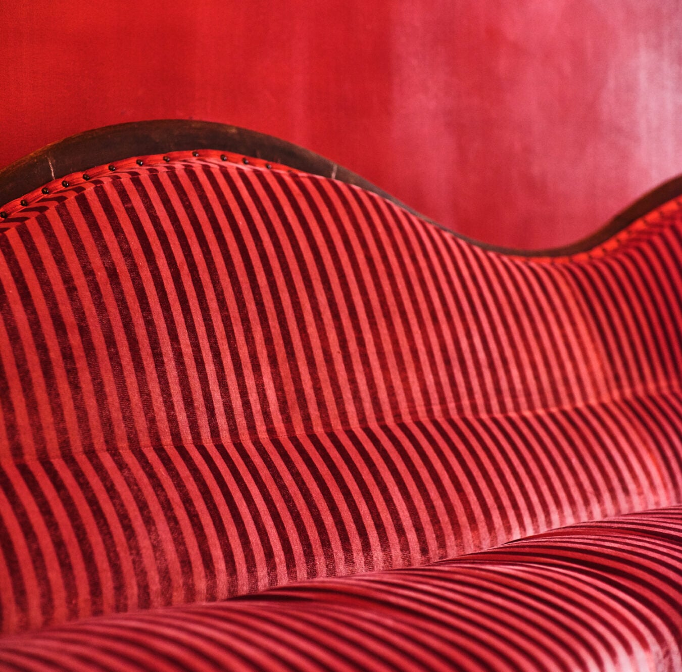 Sculptural red seating curves through the space like flowing fabric, its ribbed texture catching light in dramatic waves that transform the lounge into living art.