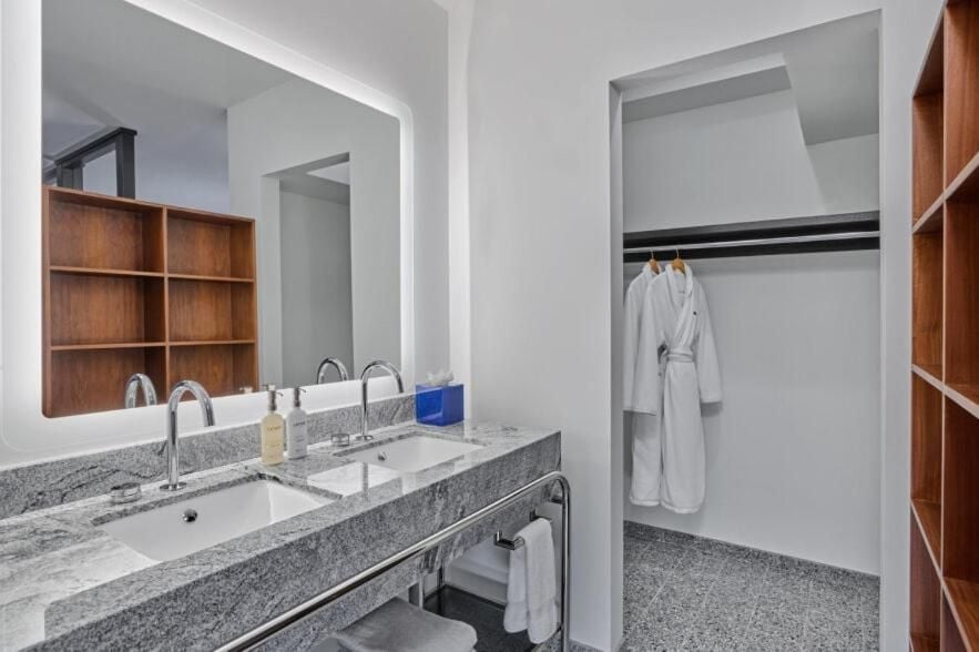 Warm walnut shelving and granite countertops create a spa-like sanctuary, where dual vanities and an adjoining walk-in closet elevate the morning ritual.