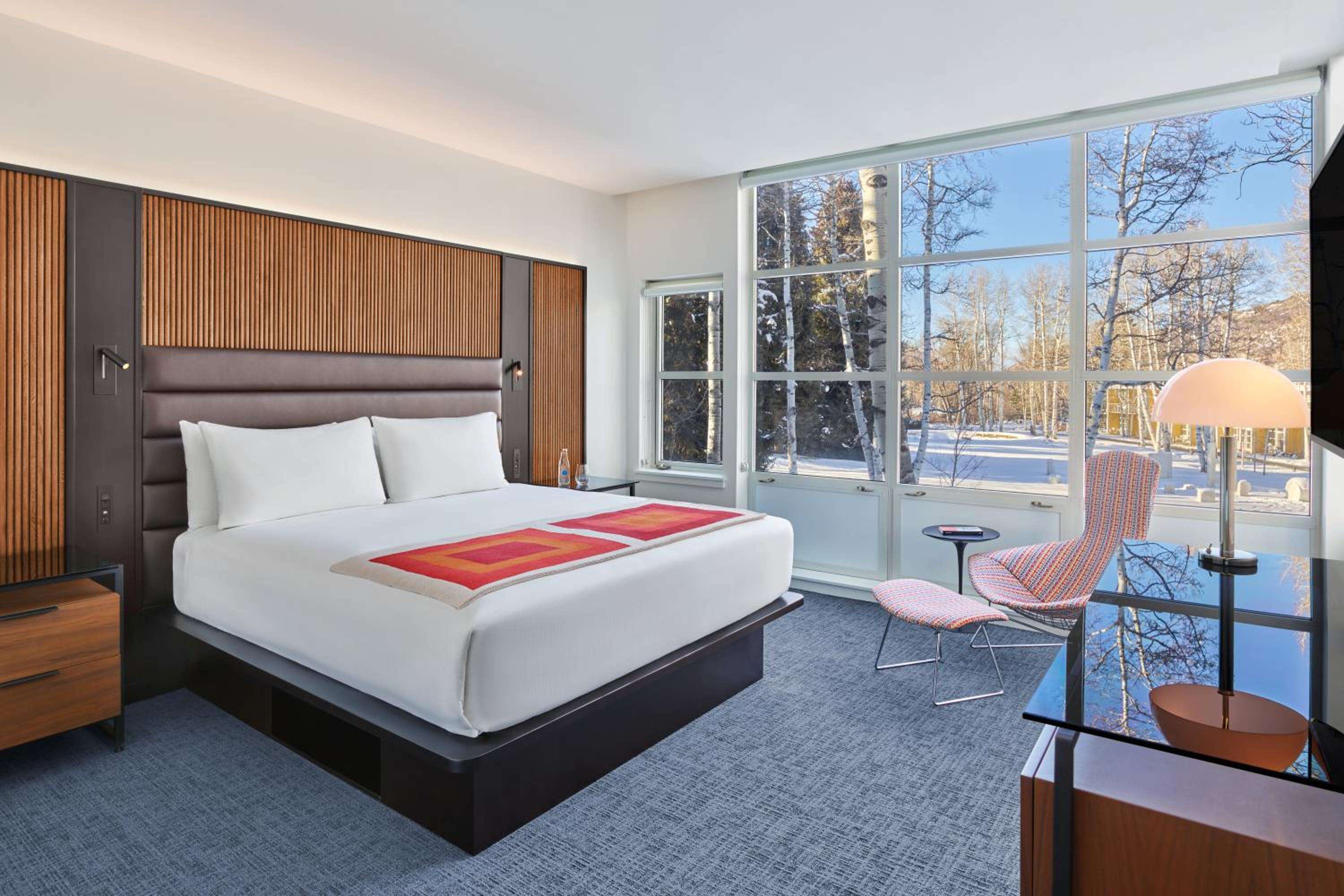 Floor-to-ceiling windows frame snow-dusted aspens while warm wood paneling and contemporary furnishings create a sophisticated mountain retreat with modern alpine sensibilities.
