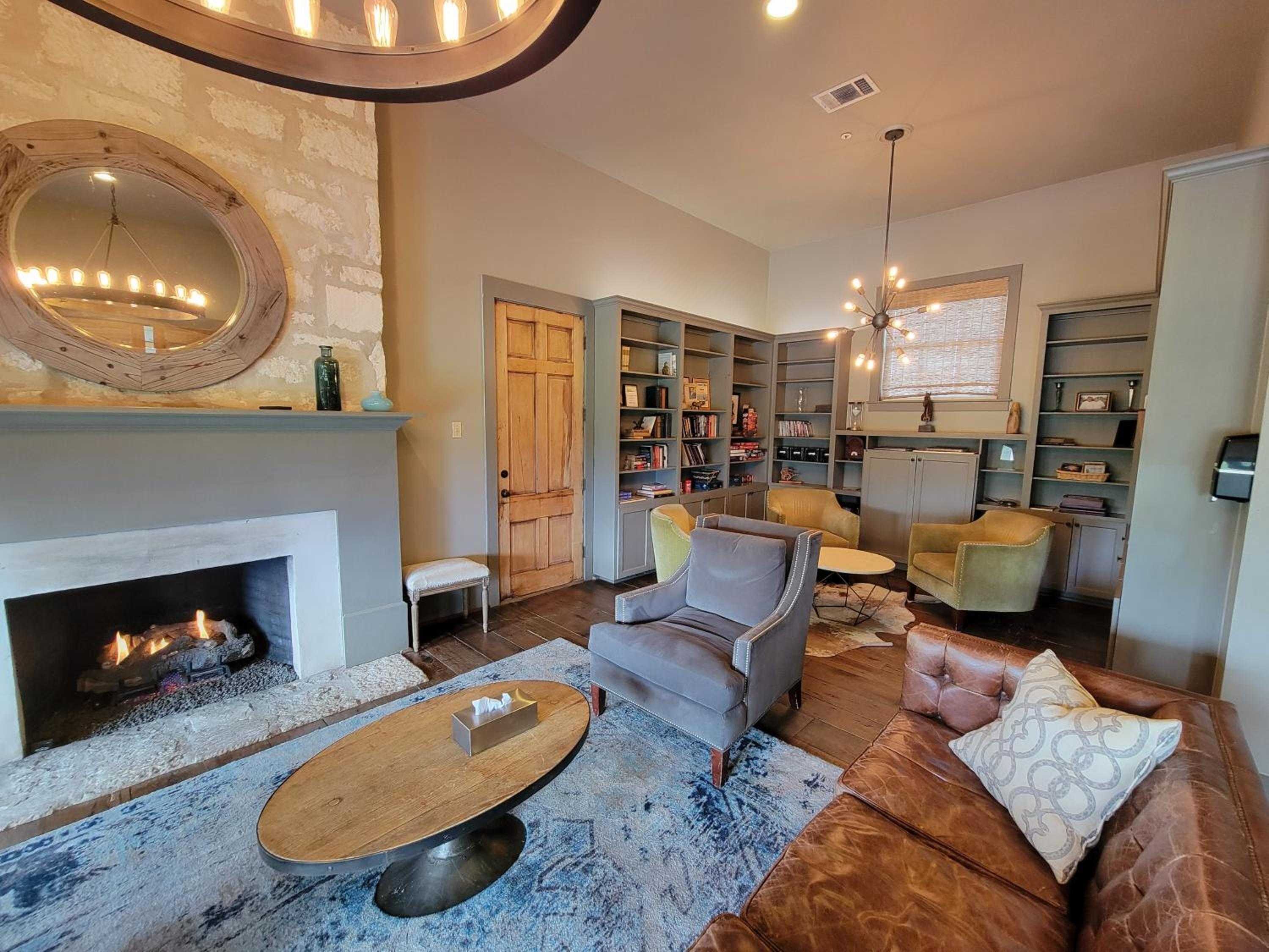 Warm firelight dances across weathered leather and worn wood in this inviting library lounge, where built-in shelves frame conversations and crackling flames.