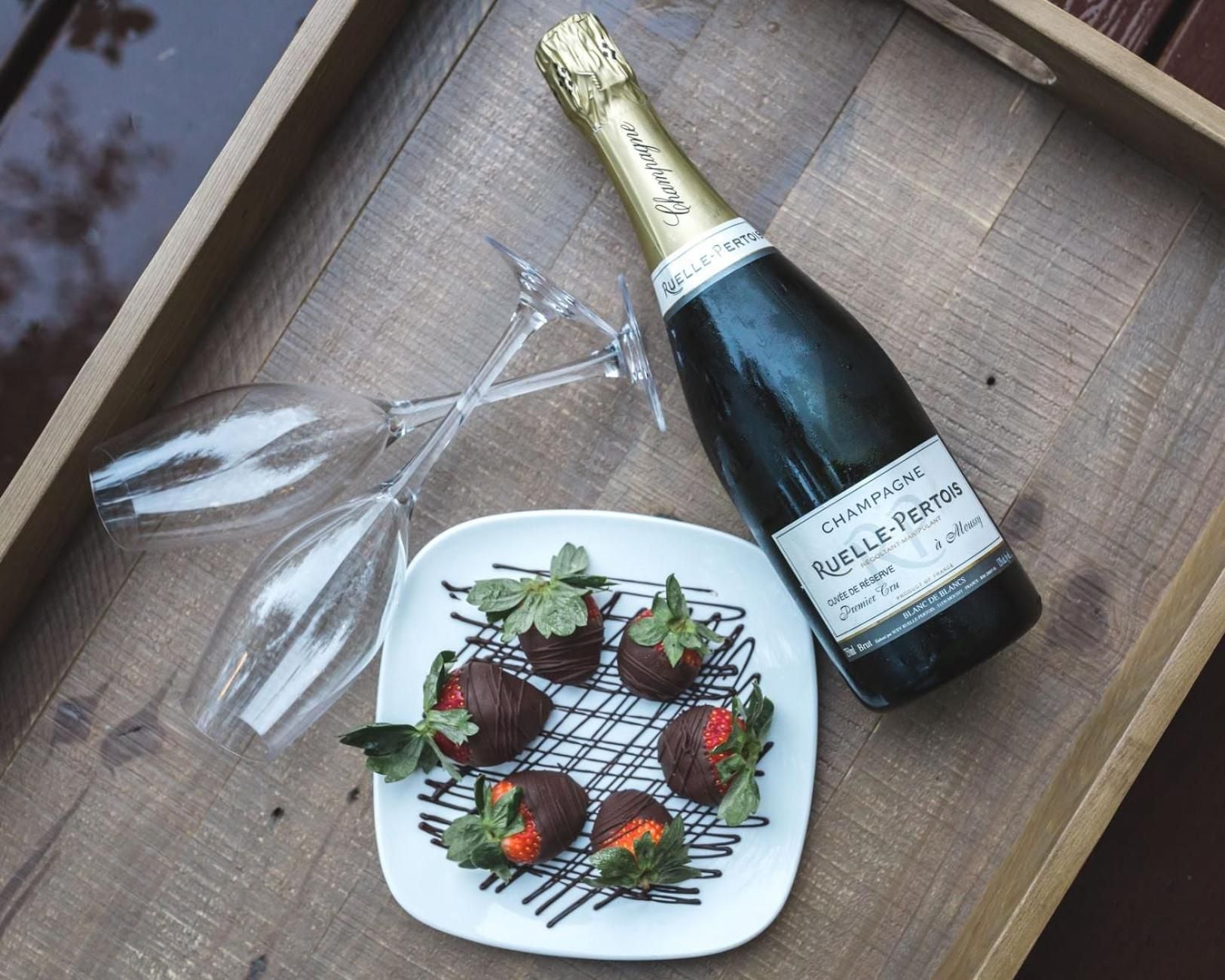 Chocolate-dipped strawberries and champagne arrive on weathered wood, creating intimate moments that define Sage Hill Inn's attention to romantic details.