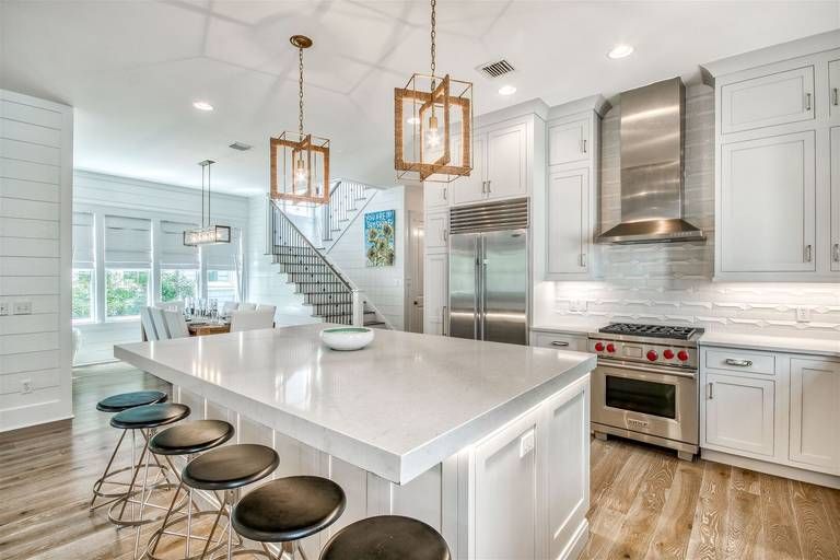 Gleaming quartz countertops and brass pendant lights create an inviting culinary haven where coastal mornings begin with coffee and ocean breezes.