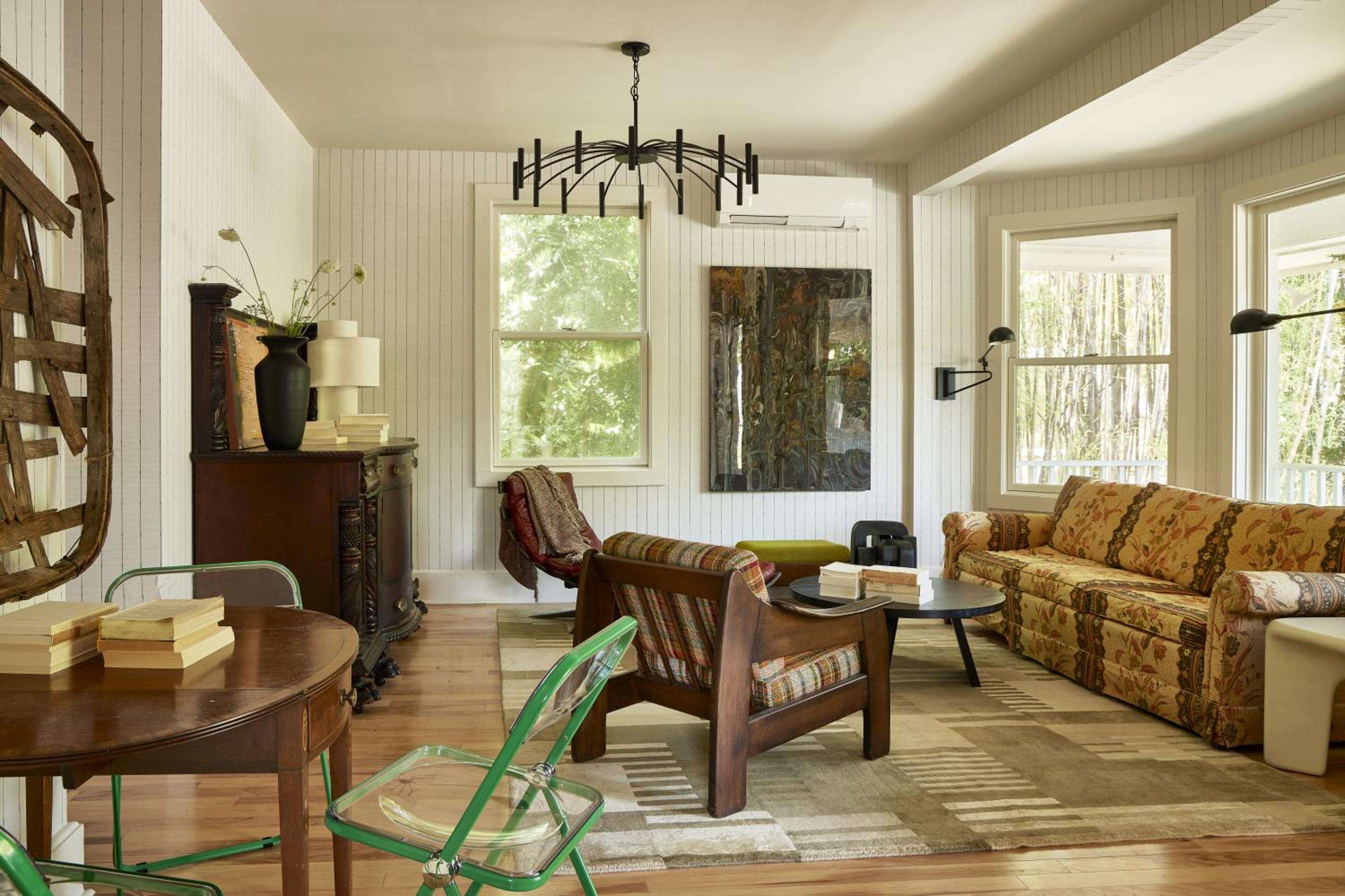 Sunlight streams through tall windows onto honey-toned hardwood floors, where vintage textiles and weathered wood furniture create an inviting retreat steeped in Appalachian charm.