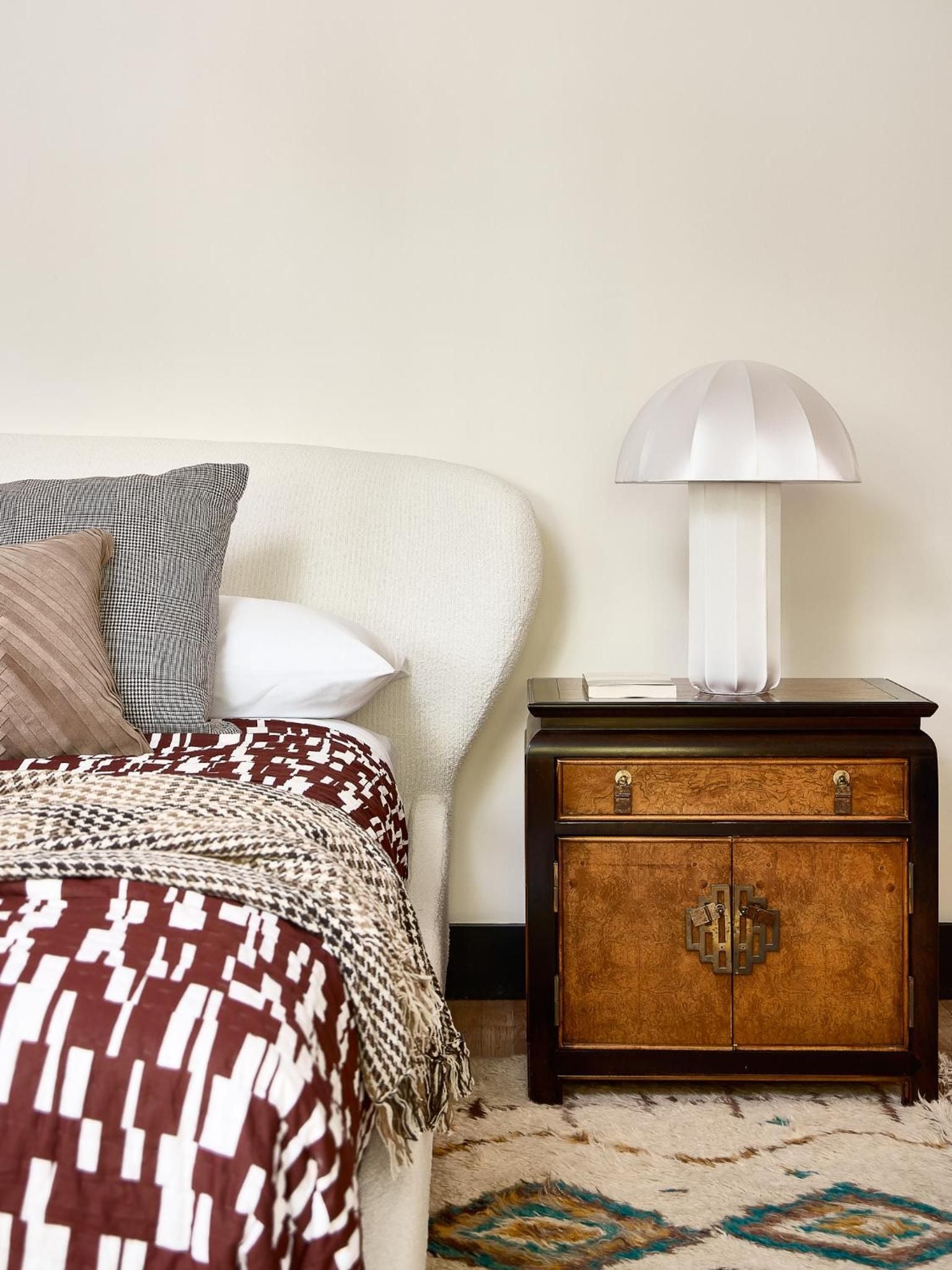 Warm textiles and vintage furnishings create an intimate sanctuary, where geometric patterns dance across burgundy throws and amber lamplight pools on burnished wood.