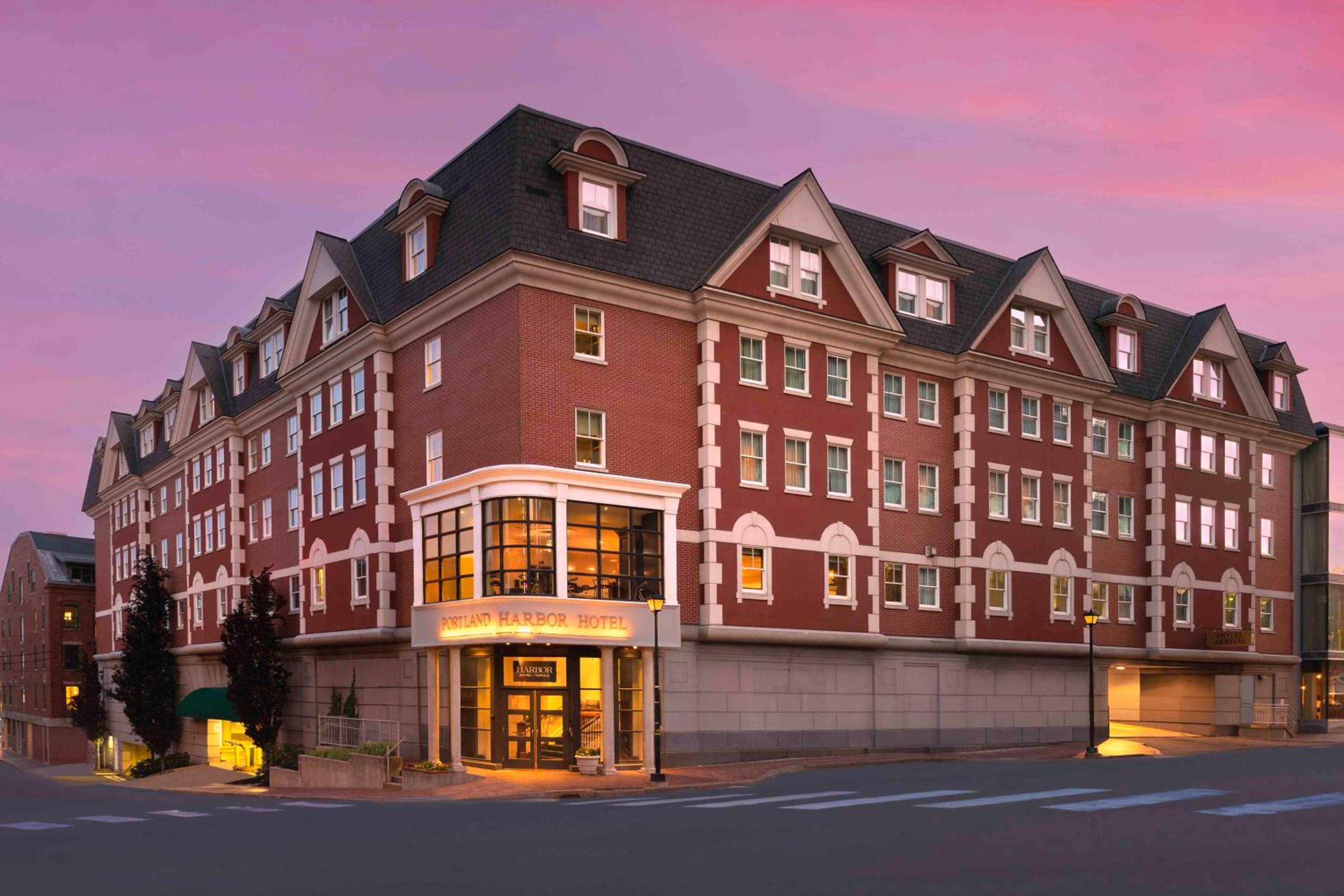 Red brick facade glows warmly against Portland's twilight sky, where classic New England architecture meets contemporary hospitality in the heart of the city.
