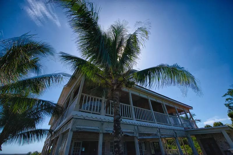 Tropical breezes rustle coconut palms beside this charming two-story colonial villa, where wraparound verandas and gingerbread trim evoke authentic Caribbean island living.