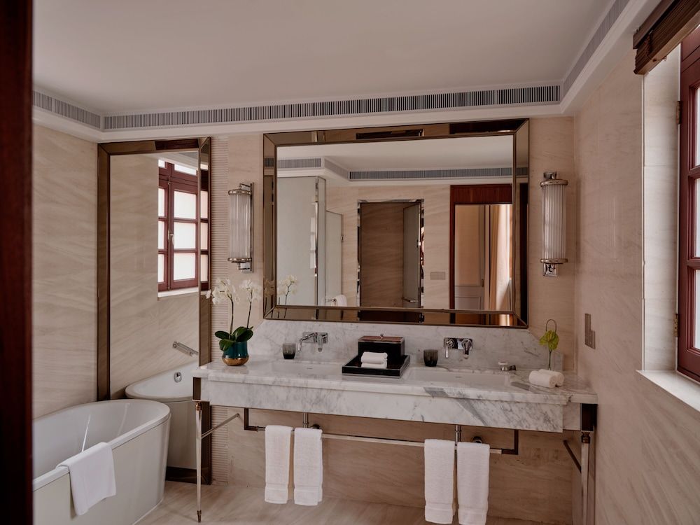 Marble surfaces gleam under soft lighting while bronze fixtures add warmth to this sophisticated bathroom, where a soaking tub invites long, luxurious retreats.
