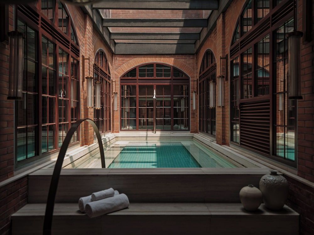 Crimson brick arches frame an intimate plunge pool where industrial heritage meets contemporary luxury in this stunning courtyard sanctuary.