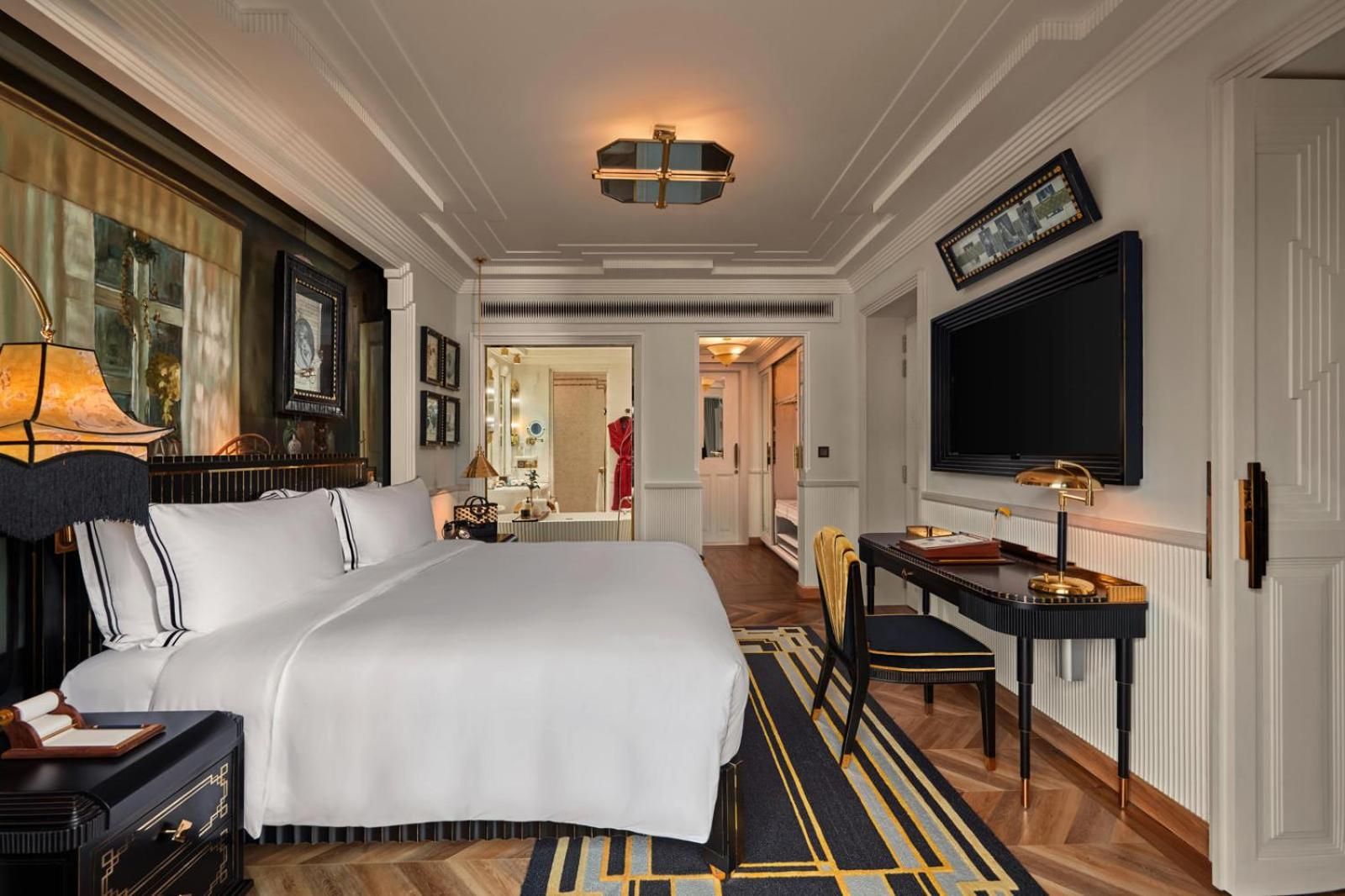 Rich navy and gold accents complement crisp white linens in this sophisticated guest room, where ornate ceiling moldings and warm wood floors create colonial-inspired luxury.