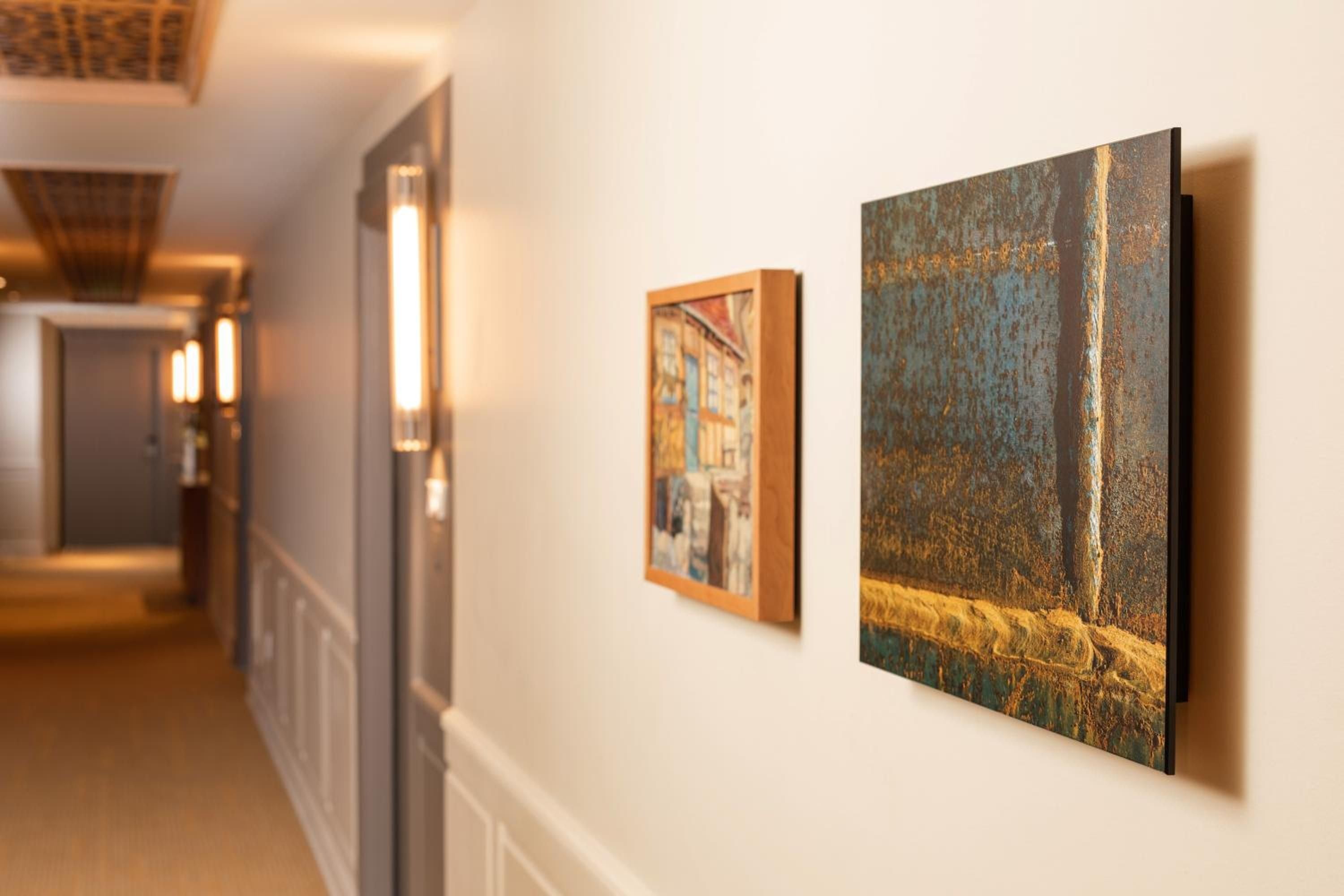 Warm sconces cast golden light along corridors where curated artwork creates an intimate gallery atmosphere, blending contemporary sophistication with Pacific Northwest warmth.