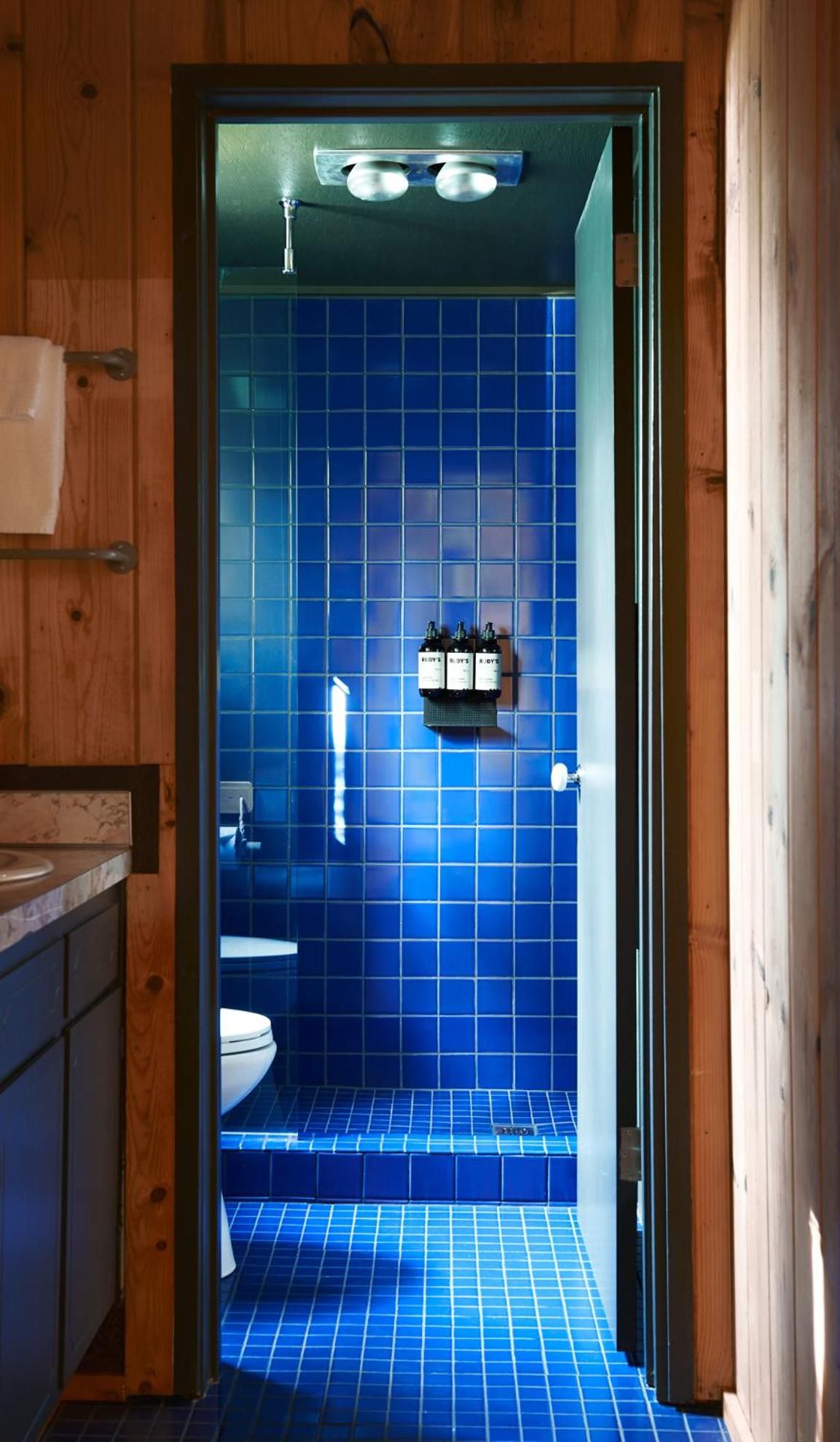 Vibrant cobalt tiles create a jewel-box shower sanctuary, where rustic cedar beams meet modern fixtures in perfect Pacific Northwest harmony.