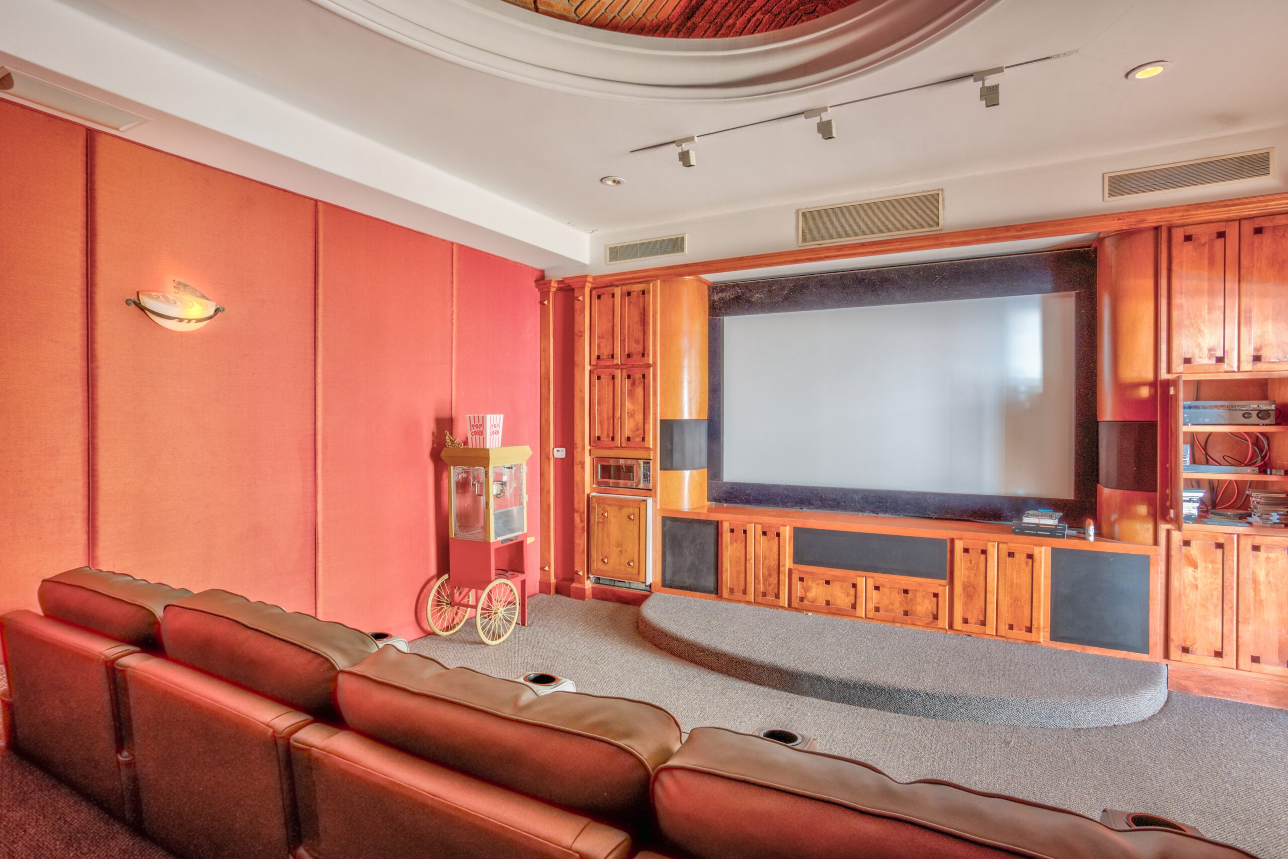 Plush leather recliners and warm wood cabinetry create an intimate screening room where guests can escape into cinematic worlds beneath softly curved ceilings.