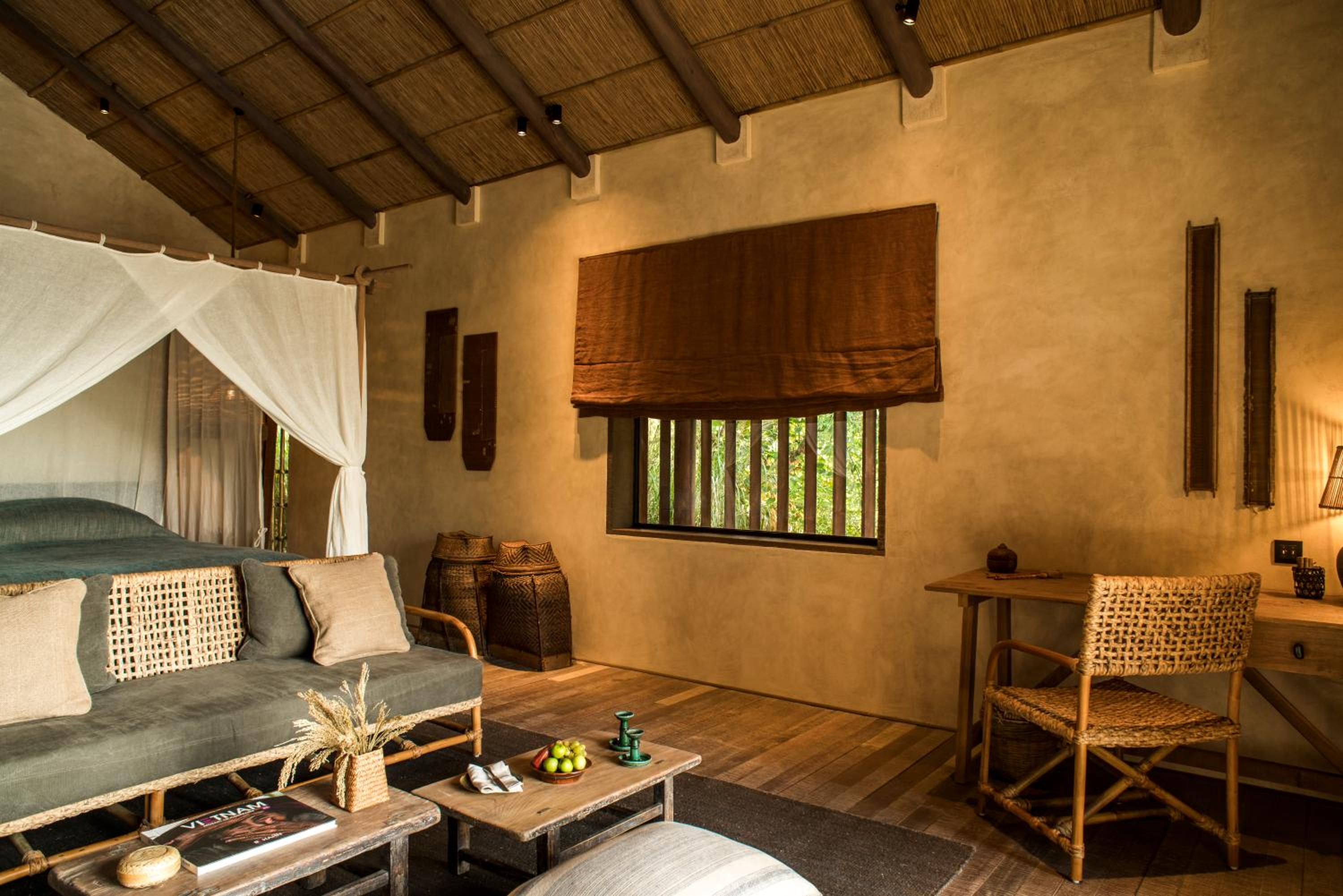 Woven rattan chairs and earthen walls create an intimate sanctuary where mosquito nets billow softly and African-inspired baskets add authentic character to this villa retreat.