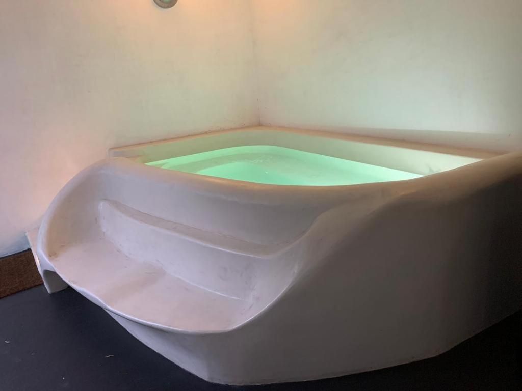 Softly glowing green light emanates from this sculptural soaking tub, creating an otherworldly cocoon where modern design meets meditative tranquility.