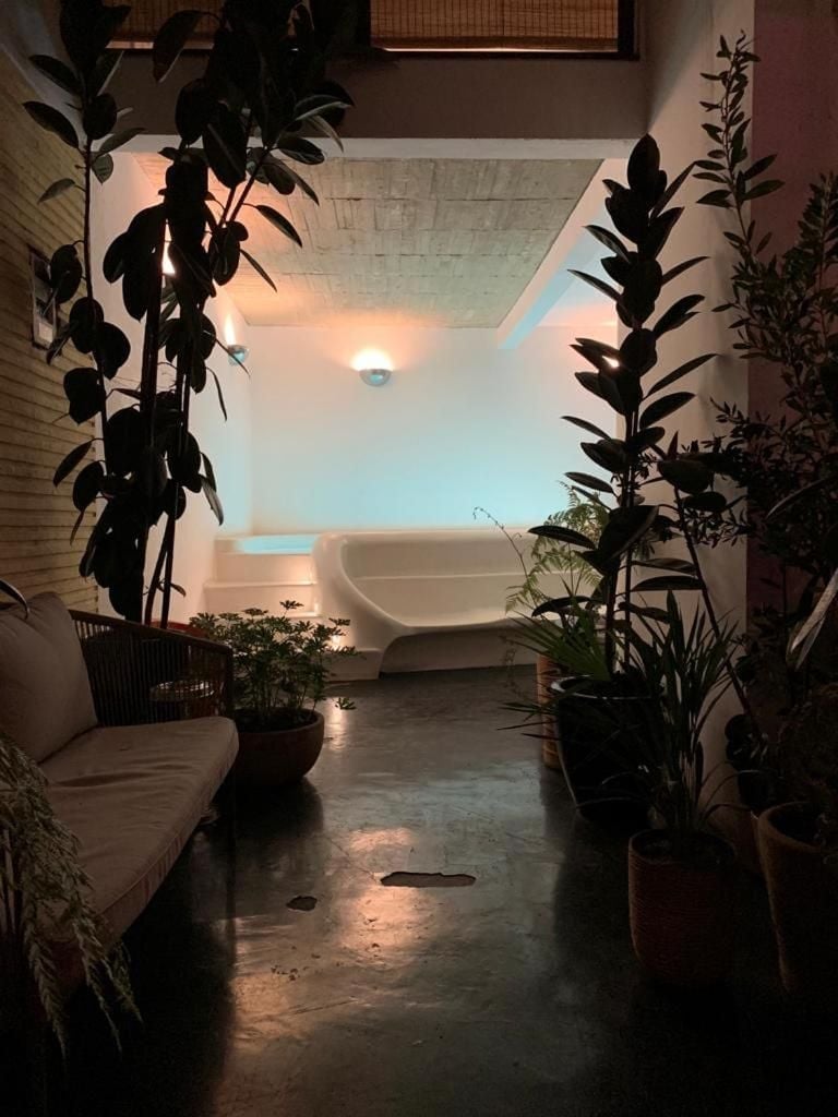 Lush tropical plants frame the serene spa sanctuary, where soft amber lighting and natural stone create an intimate wellness retreat suspended between earth and sky.