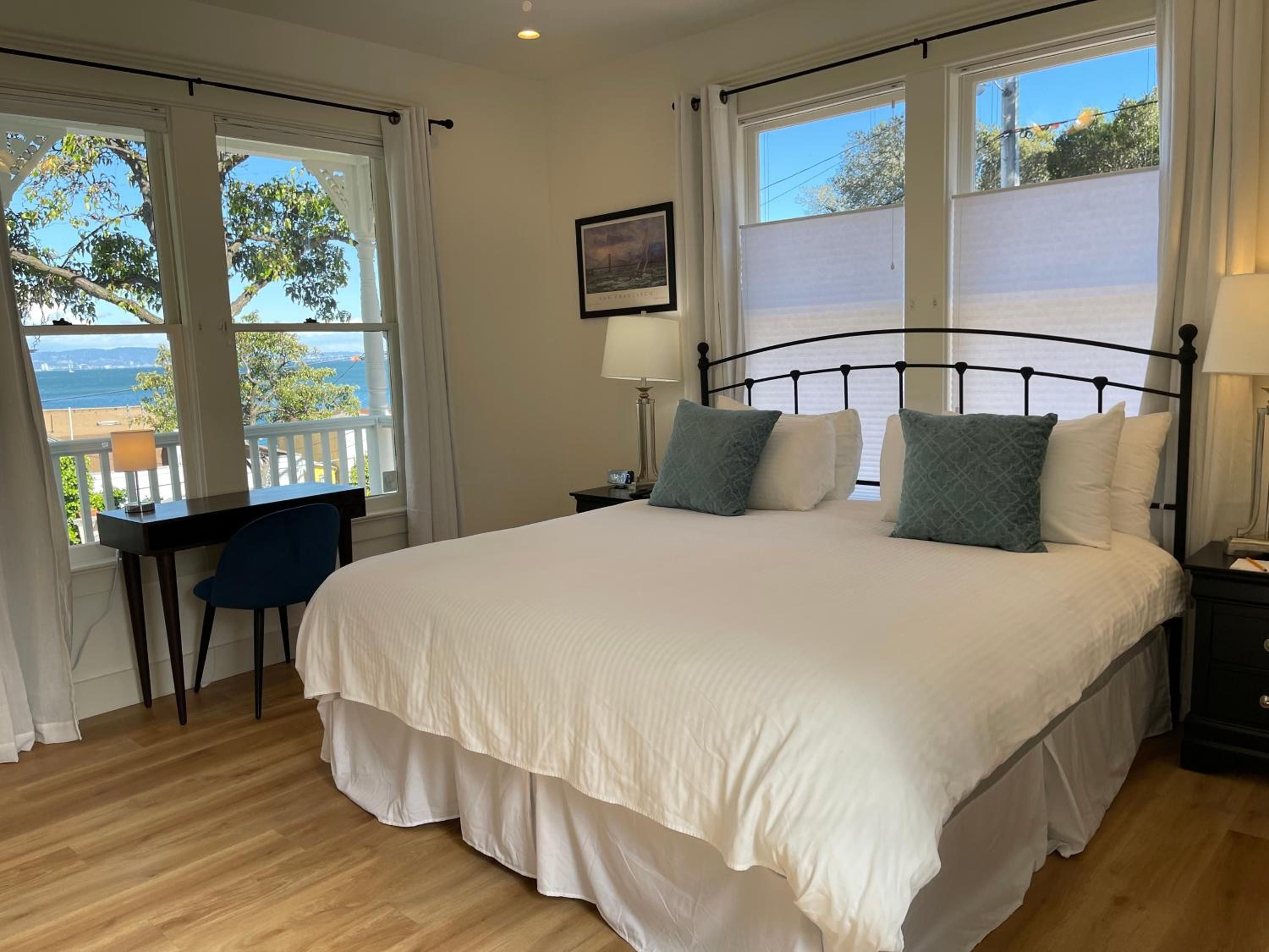 Ocean glimpses through eucalyptus trees frame this serene guest room, where crisp linens and thoughtful details create an intimate retreat overlooking San Francisco Bay.
