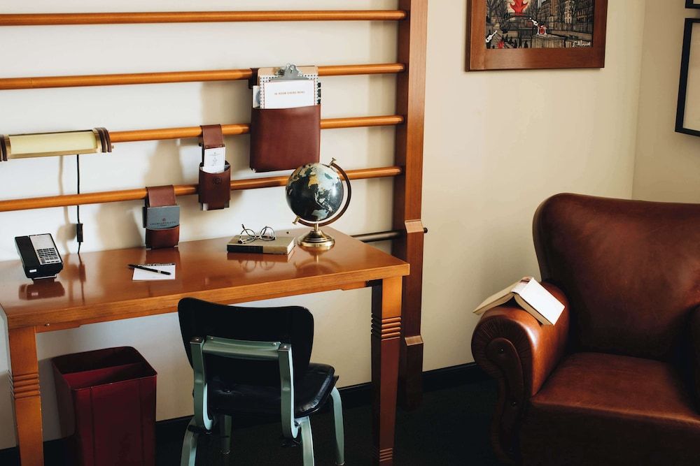 Warm wood tones and leather accents create an intimate workspace where vintage globe and slat-wall organizers blend classic club atmosphere with modern functionality.