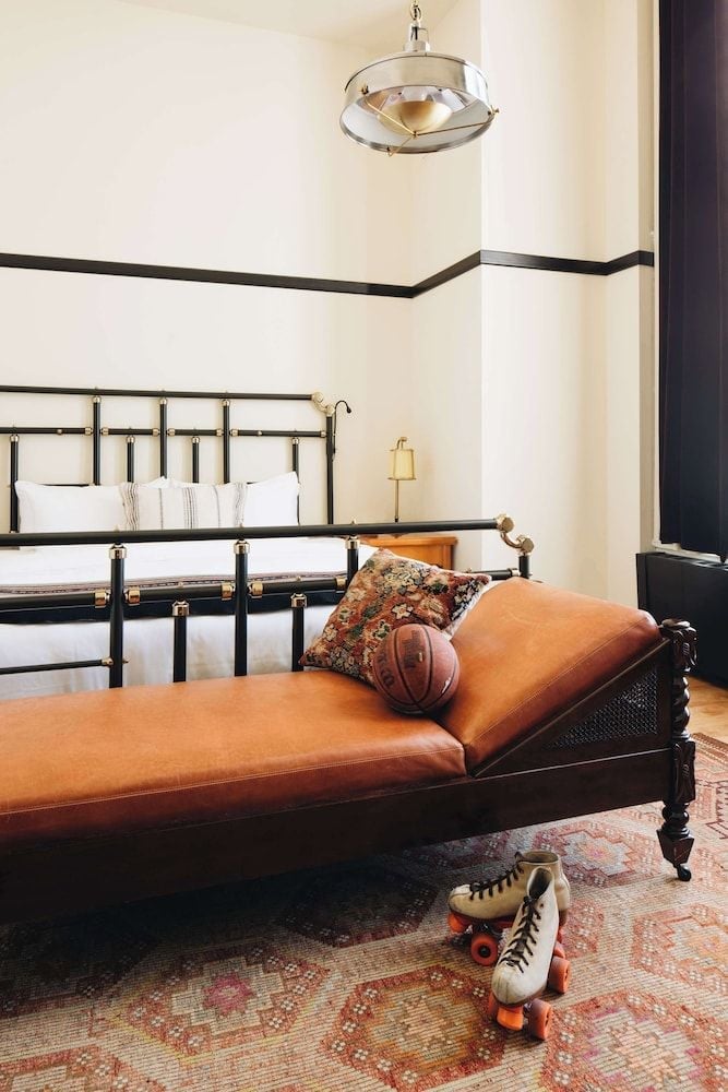 Vintage roller skates rest beside a cognac leather chaise, where brass details and striped walls evoke the nostalgic charm of Chicago's storied athletic club.