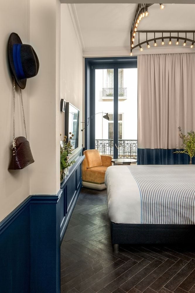 Navy blue wainscoting and warm leather seating create intimate sophistication, while string lights cast a golden glow across striped linens and herringbone floors.
