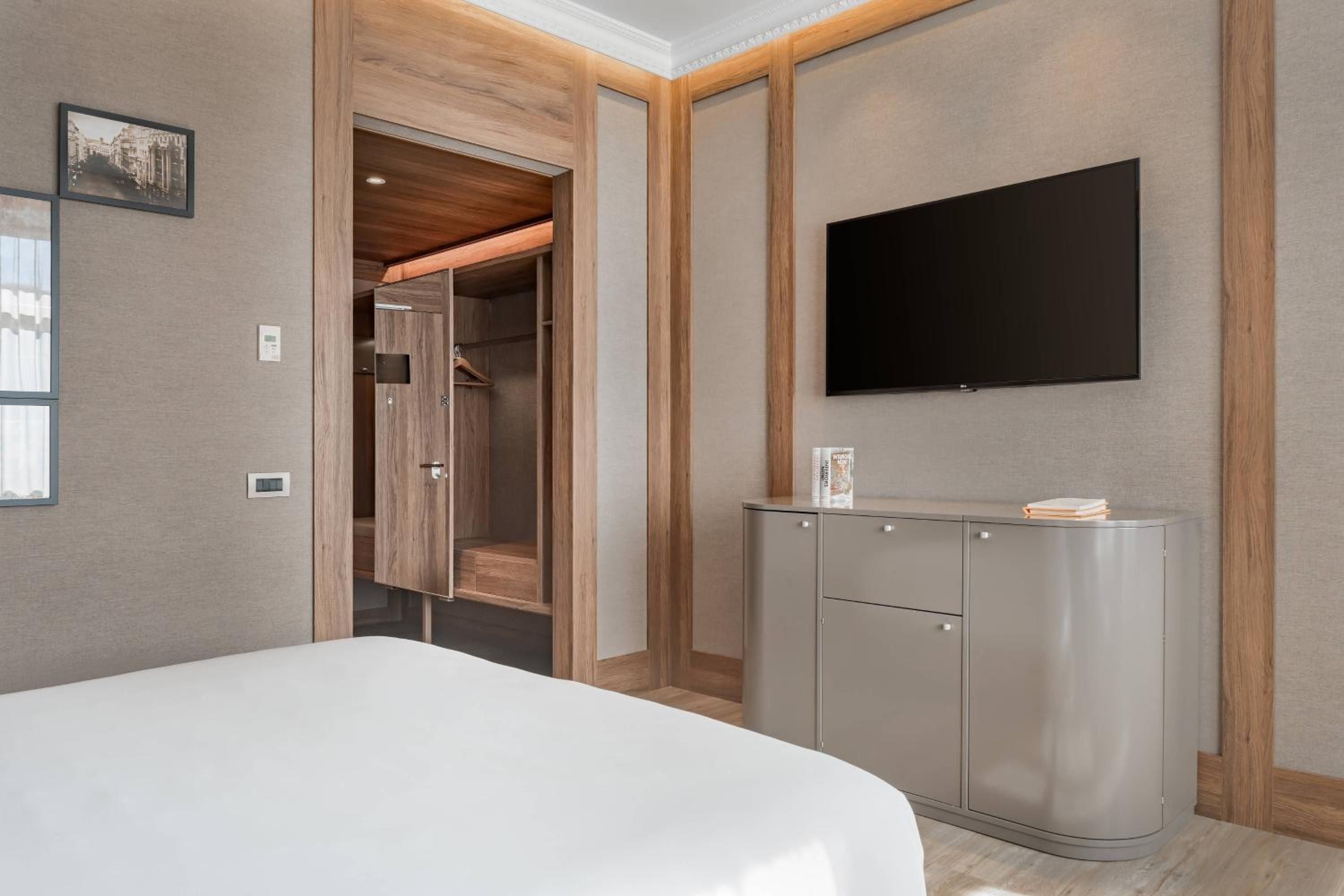 Warm wood frames and neutral tones create a sophisticated sanctuary, where contemporary furnishings meet thoughtful design in this beautifully appointed guest room.